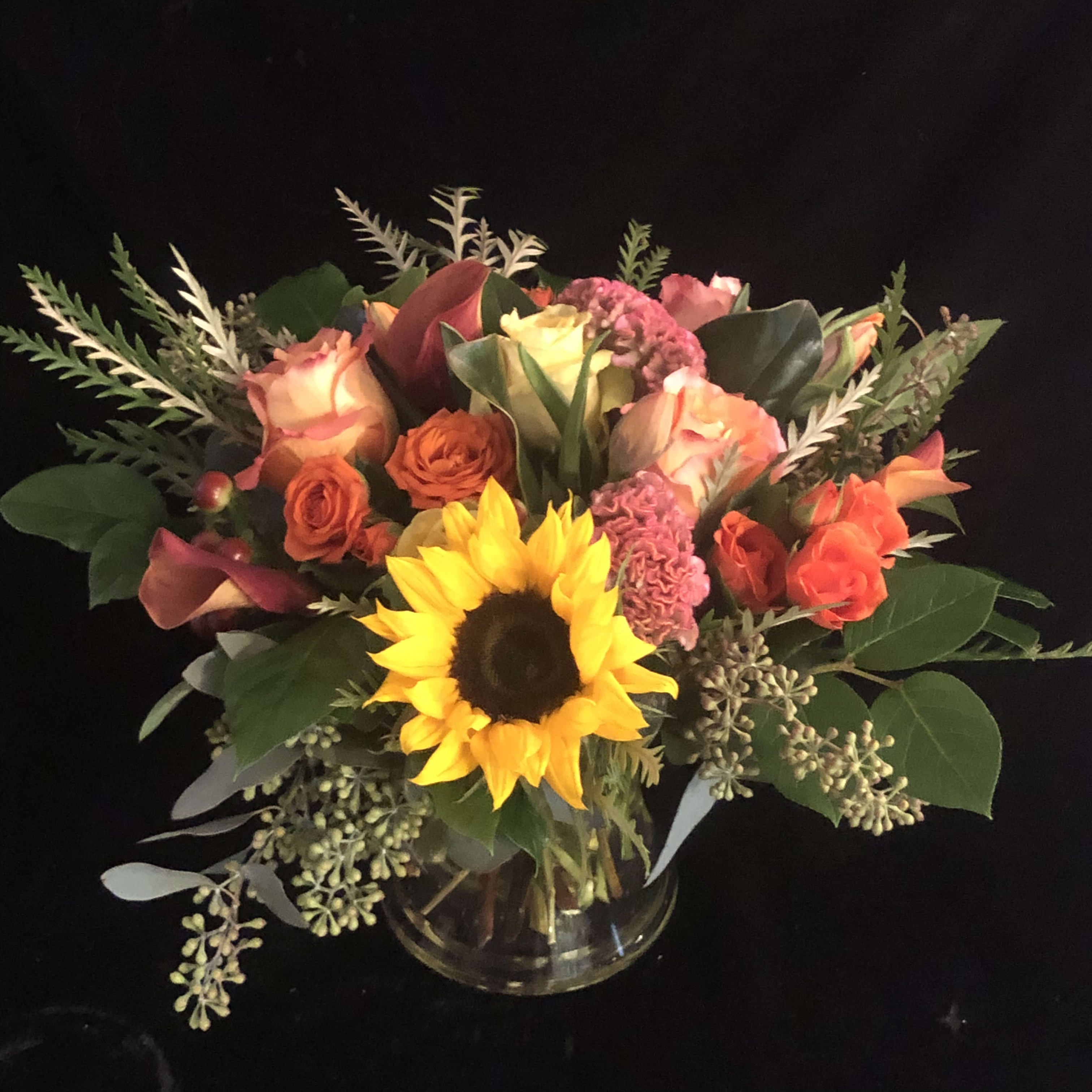 Tequila Sunrise - A beautiful combination of sunflowers, roses, coxcomb and berries and other fall flowers in gorgeous shades of orange, corals, and yellows and greens. Exact flowers may vary.