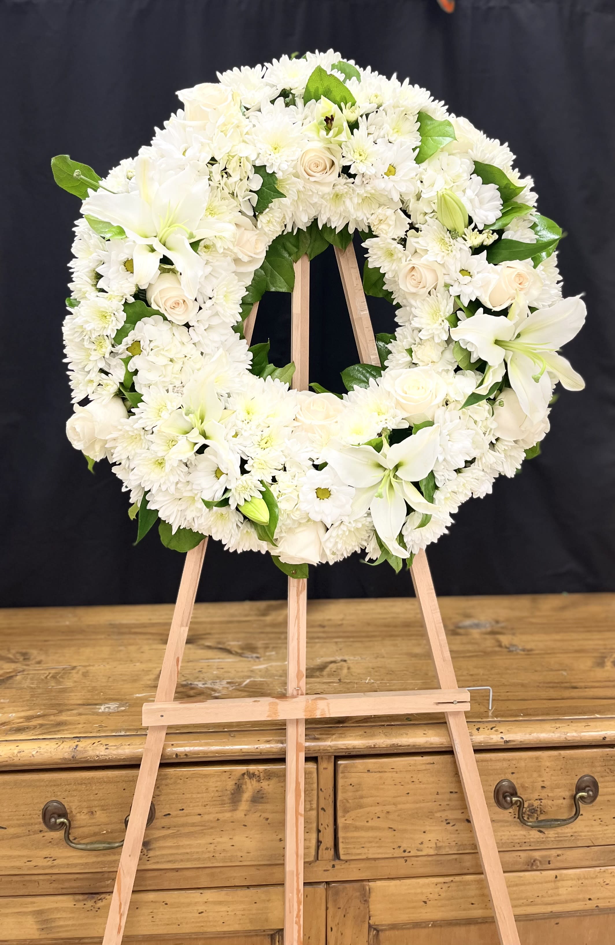 Wreath of Serenity Wreath of Serenity - Fragrant and ethereal white blossoms set among a ring of soothing greens form a classic wreath certain to evoke the pure heart and gentle spirit of a loved one - and offer consolation during a funeral or wake. Delivered on an easel, a standing wreath comprising fresh flowers such as white roses, Asiatic lilies, carnations and chrysanthemums, as well as greens including salal, Oregonia and dusty miller. Orientation: One-Sided