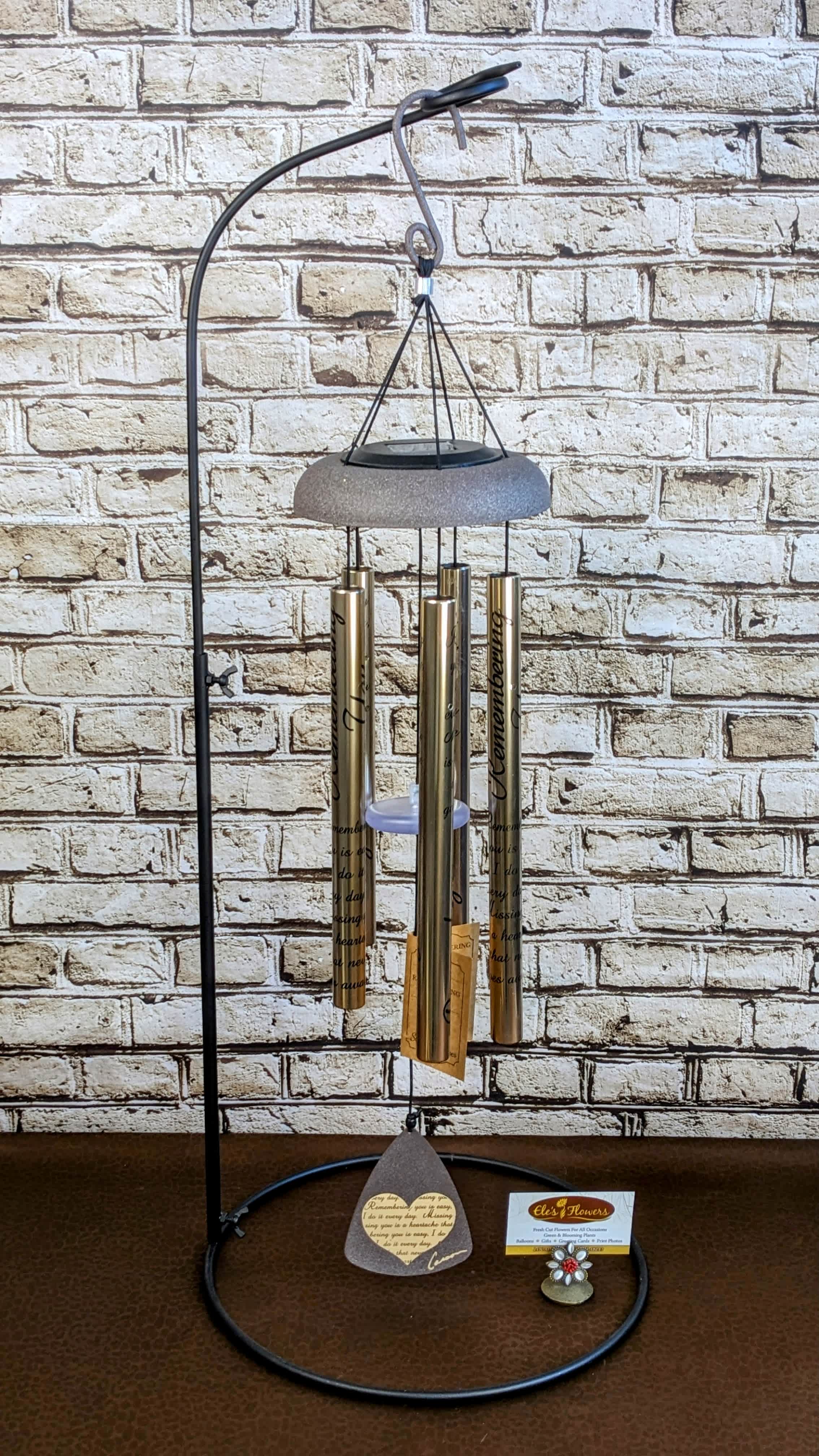 Carson Wind Chimes - 3 Size Options Carson Wind Chimes - 3 Size Options - Wind Chimes make a wonderful gift for any occasion. Tested to withstand the elements outdoors, these wind chimes will provide wonderful melodic tones as the breeze gently blows through them. We carry three different sizes and many different phrases. Please call for specifics on the phrases.  Stand shown with the chimes is a rental piece, price of chimes includes rental of the stand.  All of our chimes are dressed up for the occasion with beautiful colorful ribbon and, on request, life-like silk flowers.  We carry 3 sizes of chimes, Small, Medium and Large. Measurements are taken from the top of the hook to the very bottom of the sail.   PHOTOS SHOWN ARE FOR EXAMPLE PURPOSES ONLY Small - 30"-35" Medium -42" - 46" Large - 48" - 60"  ******* All Chimes are specific to our shop. If you're looking for these to be delivered outside of our standard delivery area, please call before placing your order. Not all shops carry wind chimes. Thank You. *******