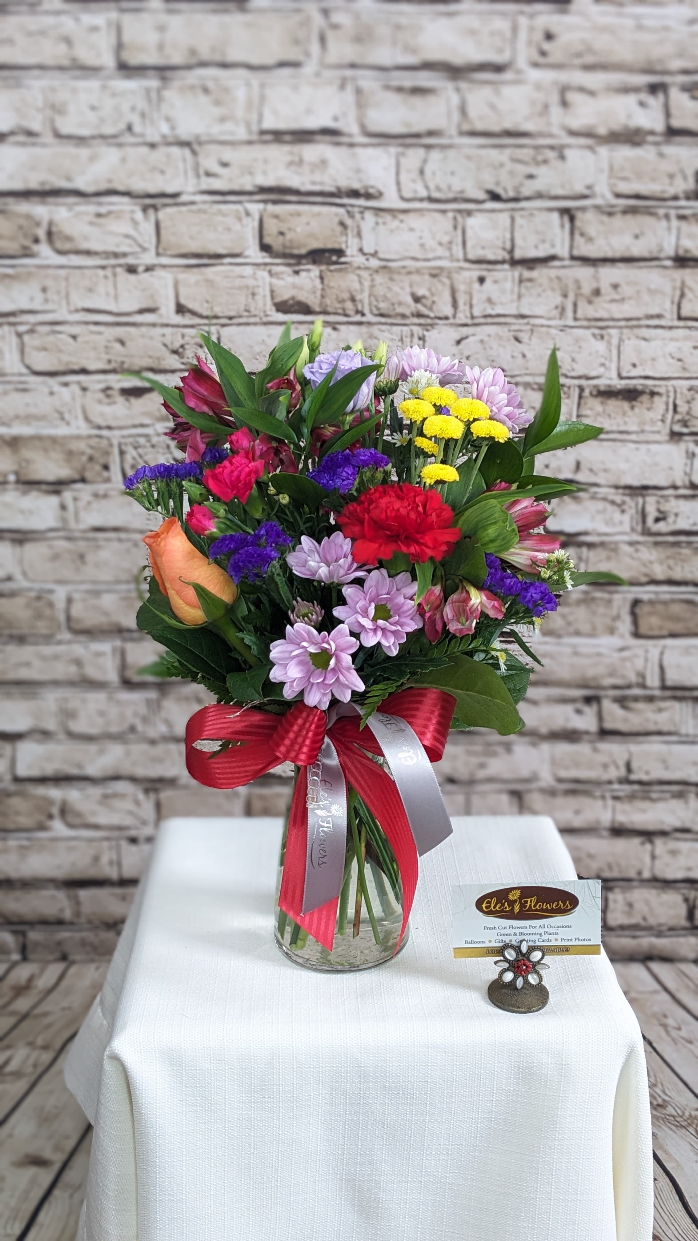 Rainbow Beauty  Rainbow Beauty  - Our Rainbow Beauty arrangement incorporates everything we love about color all in one vase. Situated among mixed textured greenery, the vibrant shades of blue, yellow, red, violet and orange blooms are sure to be enjoyed for any occasion.   The designs we create are custom and the blooms and containers will vary. We use the freshest product available to create the perfect floral combination for the recipient! If you have any special requests, please add those in the "special instructions" portion of your order to help us dial in your vision. Otherwise, our skilled designers, Brett & Sara, will take it from here! Please note that the photos are examples only – floral selection will vary.  Standard Size is an excellent desk top size or coffee table Approx. Dimensions: 12”H x 12”W  Deluxe Size is a great centerpiece size (thinking table size) Approx. Dimensions: 19”H x 14”W  Premium Size is a wonderful size for an island, showroom or office Approx. Dimensions: 25”+H x 16”+W