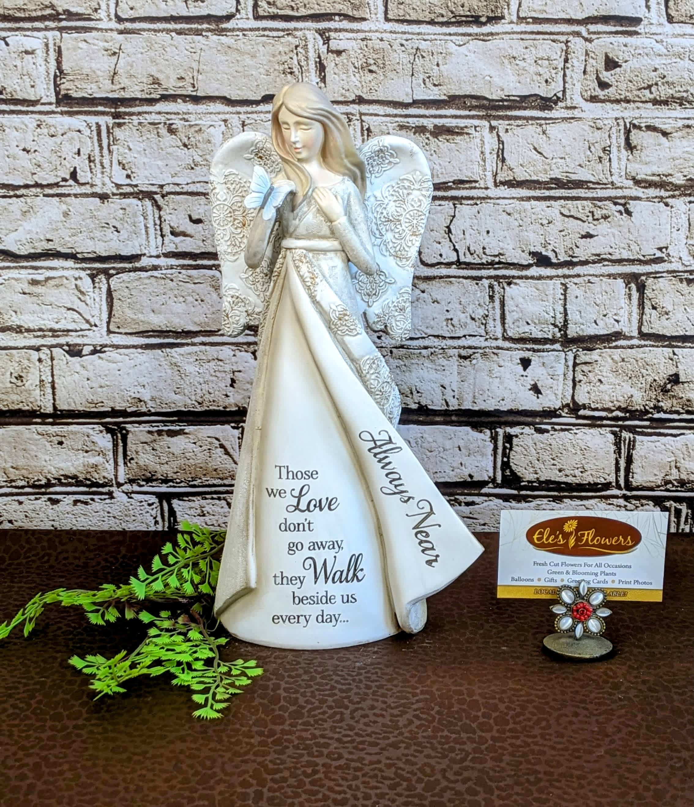 Angel Statue - Always Near Angel Statue - Always Near - Offer a heartfelt expression of compassion with our Memories Angel Statue. This beautifully crafted angel, made from high-quality resin, exudes a sense of peace and solace. With delicate wings and a serene expression, it serves as a comforting symbol of protection and love during difficult times. Perfect as a thoughtful gift or a serene addition to any space, this angel statue is a gentle reminder of support and sympathy for those who are grieving.  Angel comes with the phrase, "Those we love don't go away, they walk beside us every day.. Always near."  We are able to incorporate this statue within a floral display. Please inquire with us for options. Approximate Dimensions: 12"H x 6"W