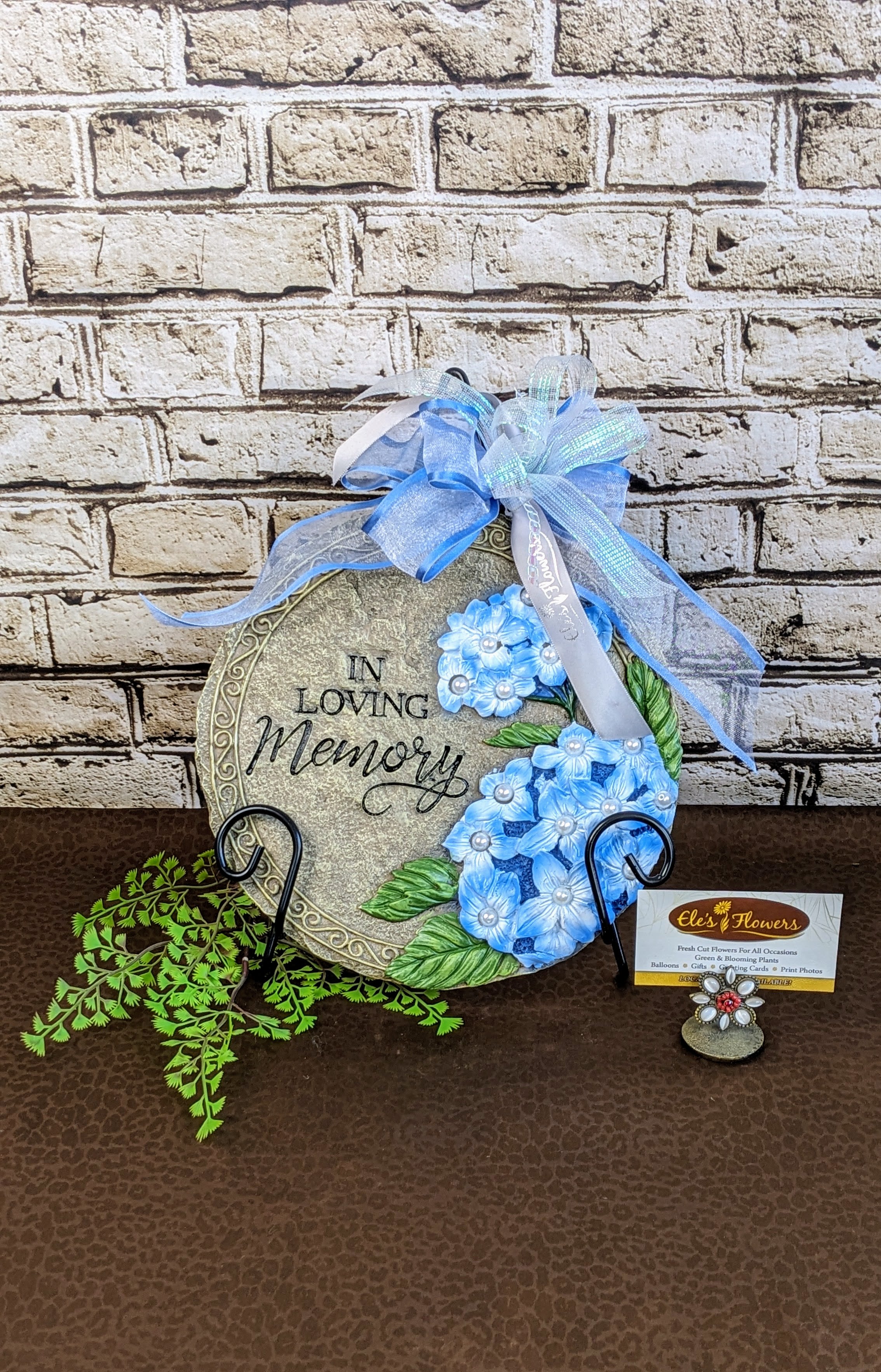 Sympathy Stone - In Loving Memory Sympathy Stone - In Loving Memory - A sympathy stone is a heartfelt memorial gift, crafted from durable resin. Engraved with comforting words, symbols, and images, it serves as a lasting tribute to a loved one, providing solace during times of grief. Perfect for gardens, memorial areas, or indoor displays, this stone is a meaningful reminder of love, loss, and cherished memories.  This stone has the phrase, "In Loving Memory." Stand included.   Approximate Dimensions: 9"H x 9"W