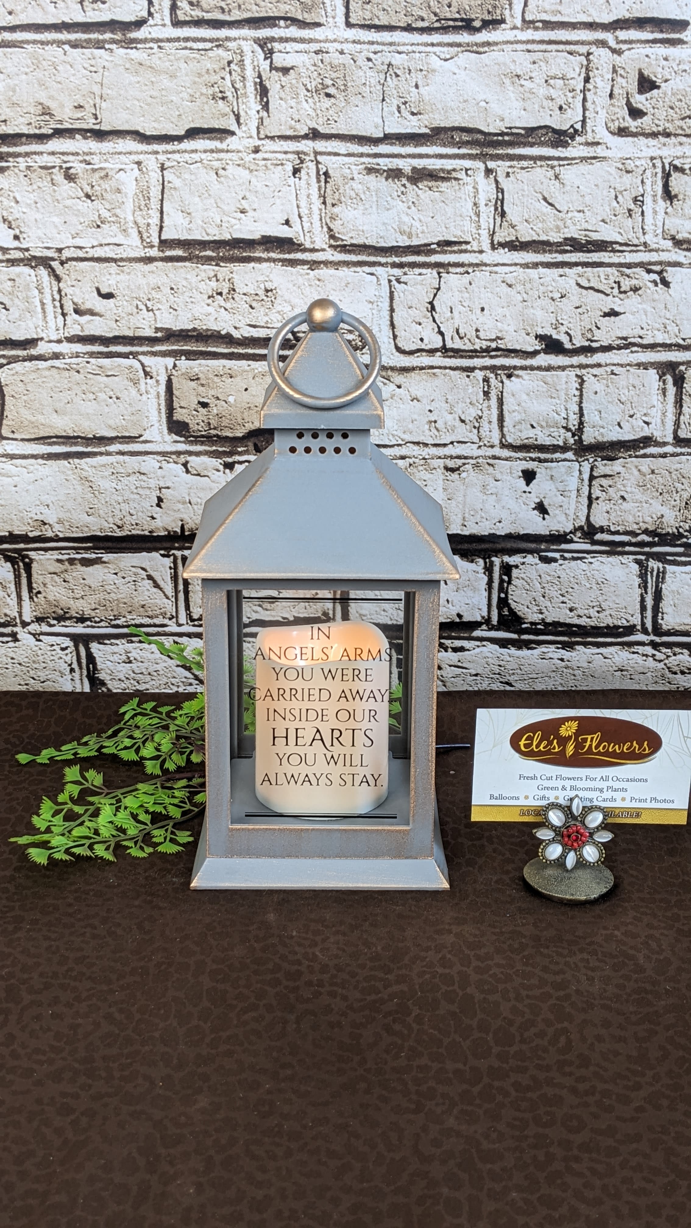 Sympathy Lantern - Angels Arms Sympathy Lantern - Angels Arms - A keepsake sympathy lantern with an LED flicker candle is a thoughtful memorial piece designed to provide comfort and remembrance. Made from durable plastic, the lantern features a timeless design with clear panels that allow the gentle, realistic flicker of an LED candle to shine through. This lantern serves as a lasting tribute, offering a warm and comforting glow that symbolizes enduring love and cherished memories. Ideal for indoor or outdoor display, it’s a meaningful way to honor a loved one’s memory.  This lantern has the phrase, "In Angels arms you were carried away, inside our hearts you will always stay."  Approximate Dimensions: 9.5"H x 4"W