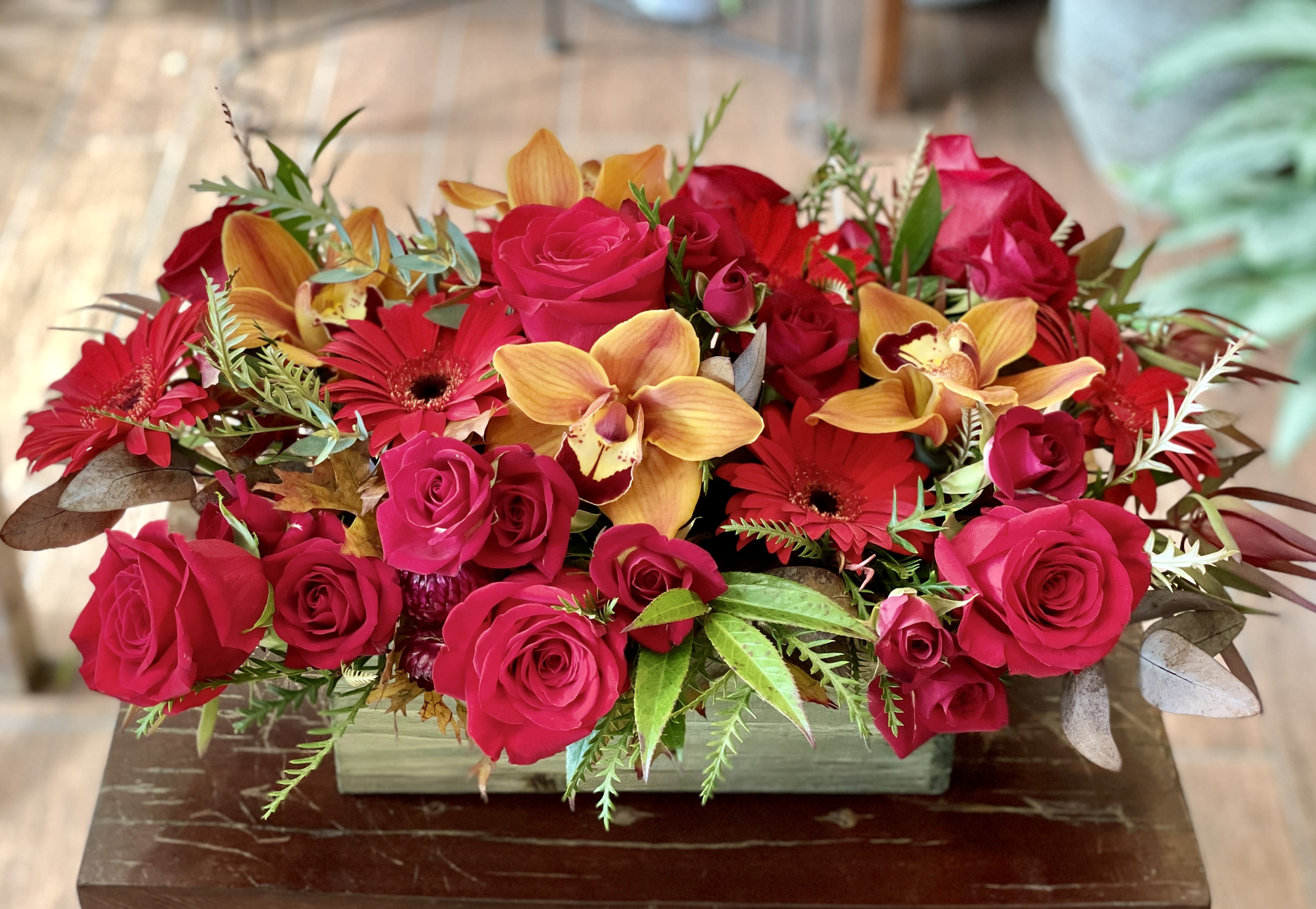 Abigail - Red and gold blooms arranged in a wooden box.