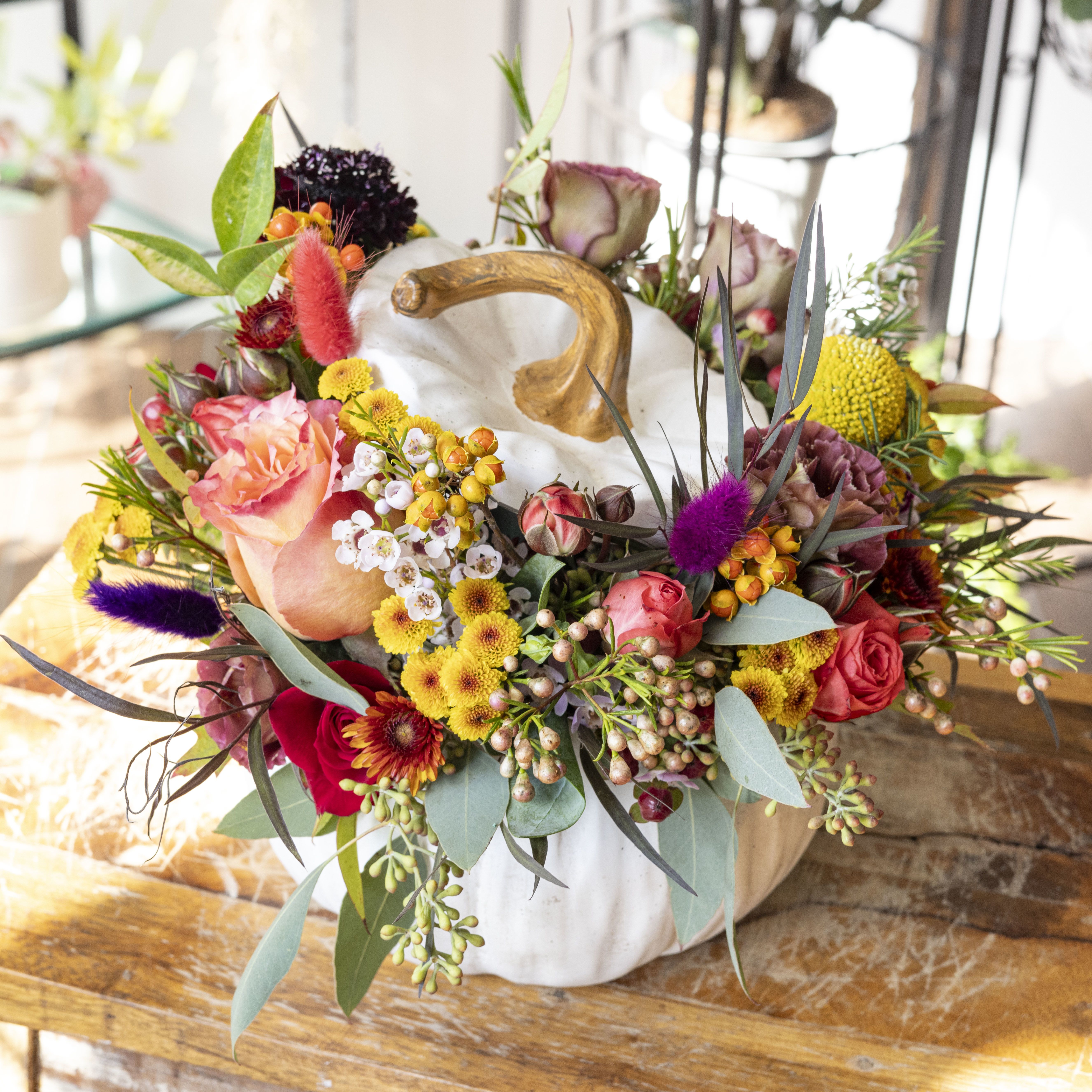 Eloise - Ceramic pumpkin centerpiece with assorted autumn toned flowers.