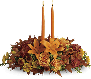 Family Gathering Centerpiece Family Gathering Centerpiece - As your loved ones gather around the table, they'll bask in the warm glow of two orange taper candles surrounded by a fantastic array of fall flowers. Orange roses, asiatic lilies, dark orange alstroemeria, bronze button spray chrysanthemums, yellow and rust cushion spray chrysanthemums and fall foliage are exquisitely gathered in this center-of-attention piece.