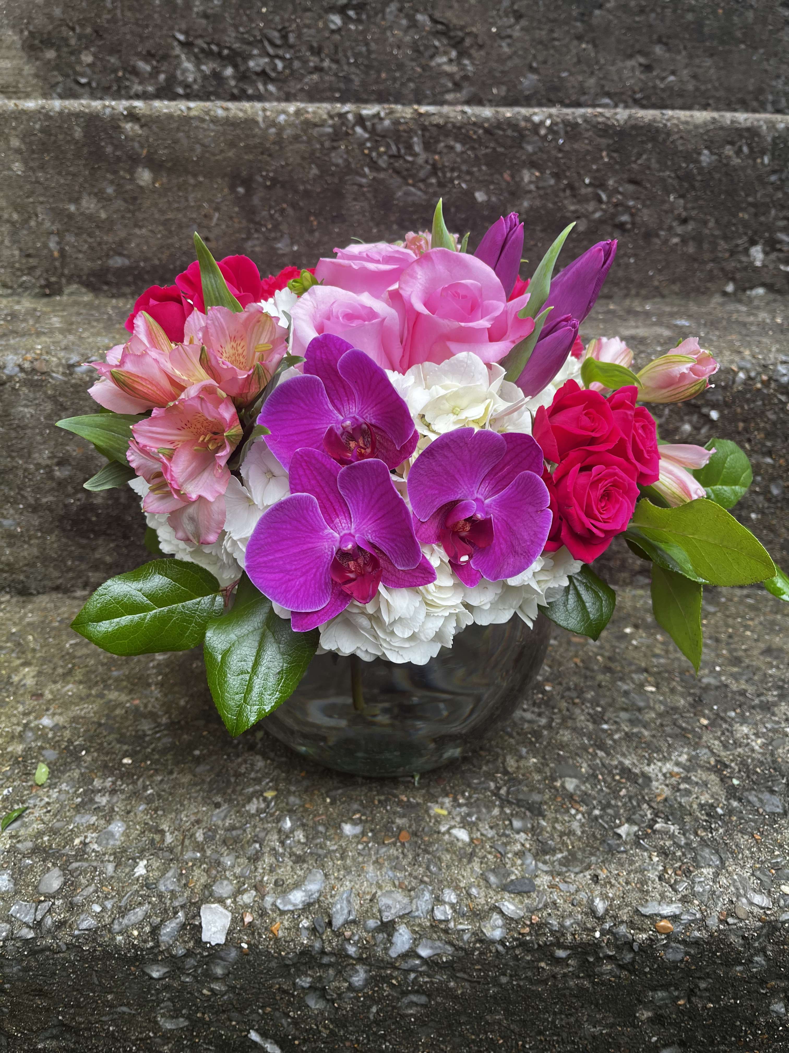 Majestic Majestic - This arrangement has three Orchid, hydrangeas, roses, spray roses, alstroemeria, tulips and beautiful greenery. The Orchid color may be changed due to availability.