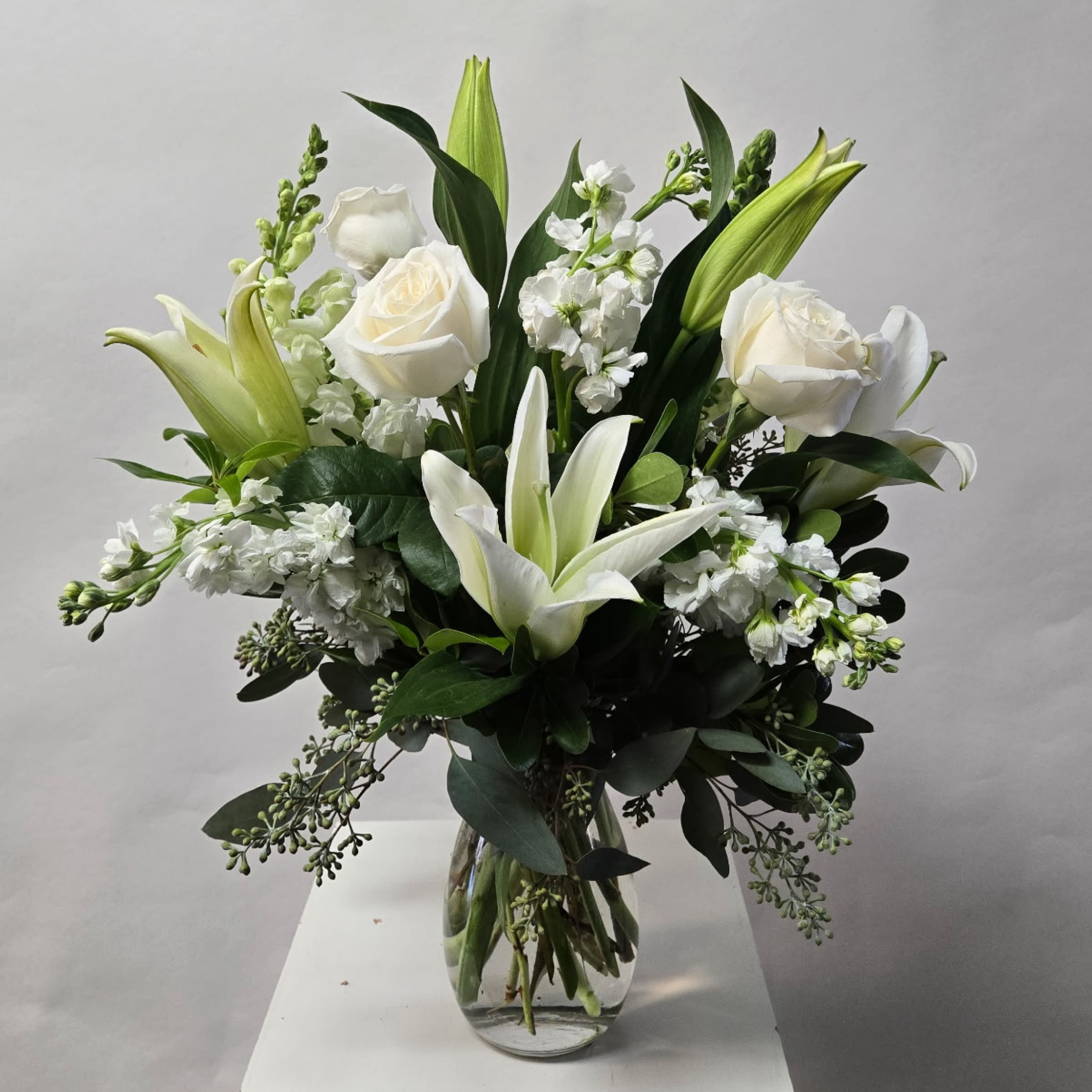 Timeless Classic Timeless Classic - This Medium Sized Arrangement Includes White Lilies, White Roses, White Stock and White Snapdragons. Or as Similar as Possible.