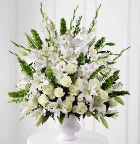 SFW 7-21 Arrangement SFW 7-21 Arrangement - An all white sympathy arrangement featuring fresh white blooms and arranged with mixed greenery into a tall white container.