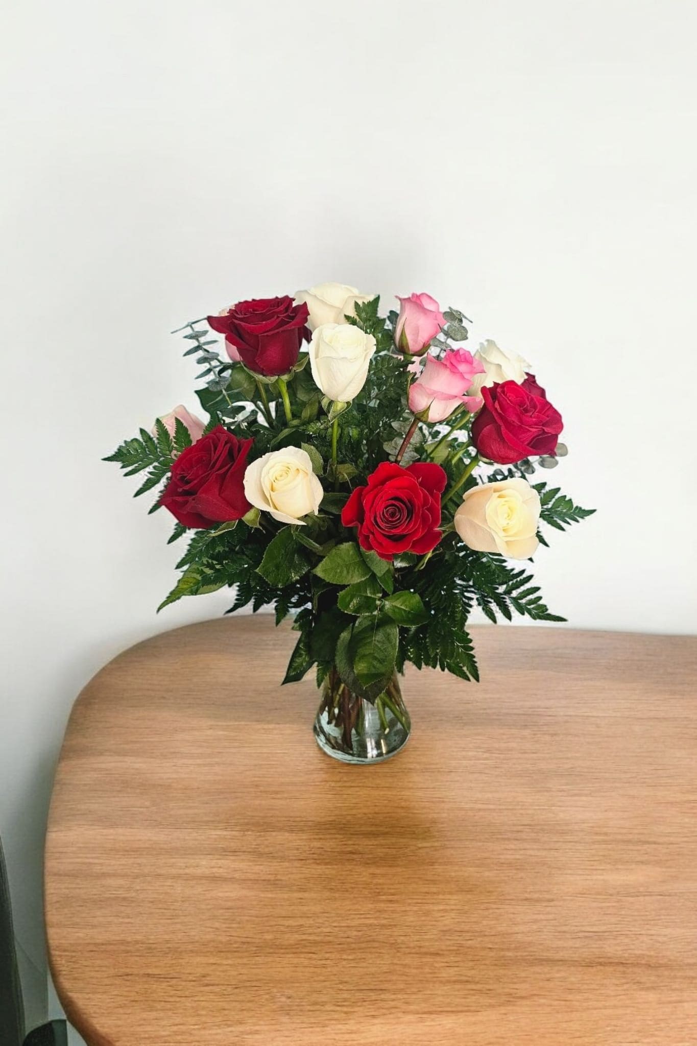 Assorted Roses - These Assorted Roses are a beautiful choice for any occasion. With 12 roses, each one carefully selected and paired with fine greenery, this bouquet is sure to make a statement. The clear vase adds a touch of elegance to the vibrant colors. Perfect for expressing your feelings with a classic and timeless gift.