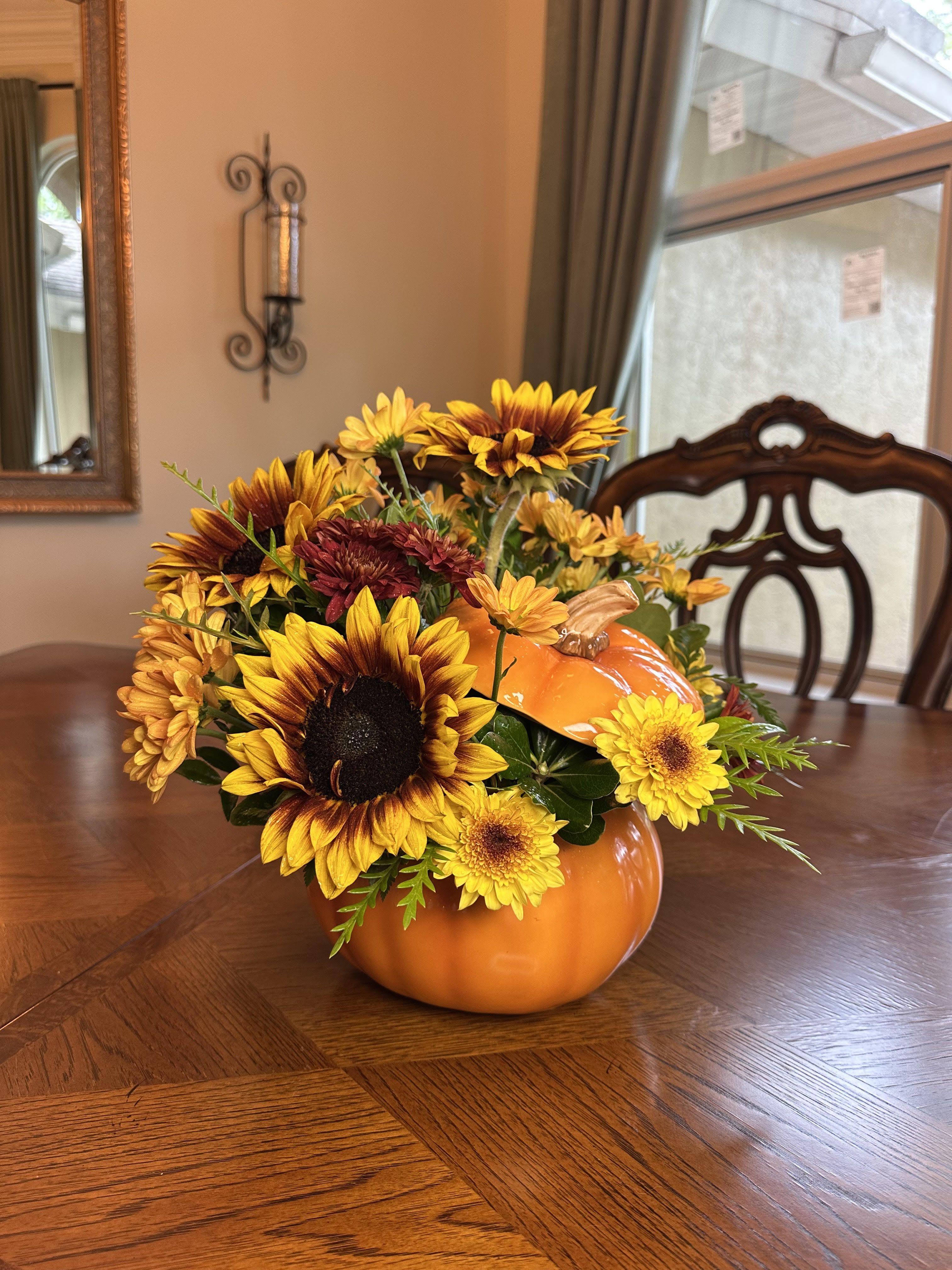 Pumpkin Patch Delight Pumpkin Patch Delight - Celebrate the season with our Pumpkin Patch Delight arrangement! Bursting with golden sunflowers, warm-toned mums, and cheerful seasonal blooms, this design is artfully arranged in a festive ceramic pumpkin container. Perfect as a centerpiece for your fall table, a thoughtful hostess gift, or a cheerful way to welcome autumn into your home.