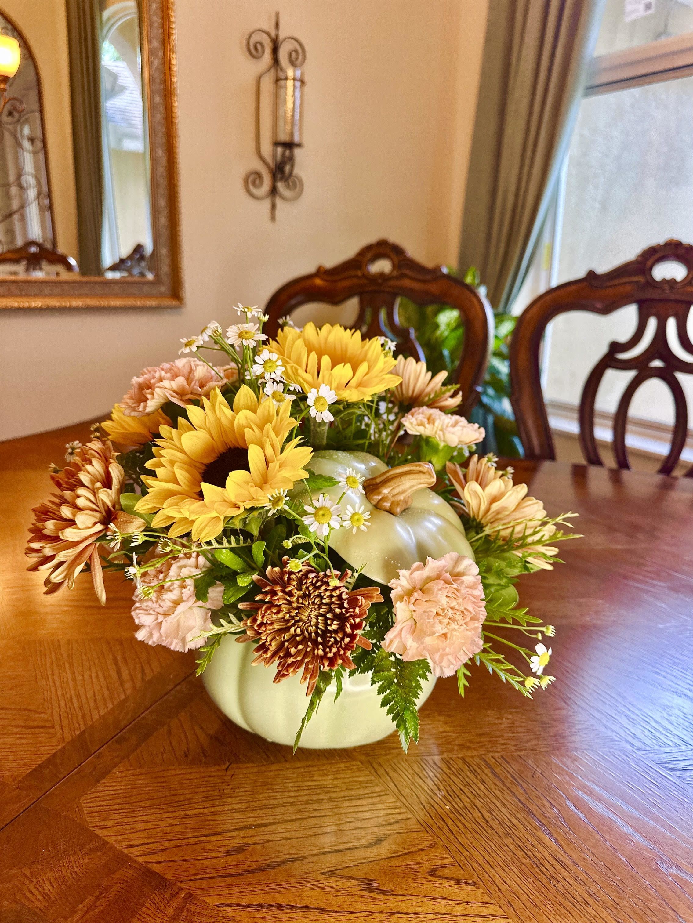Autumn Elegance Pumpkin Autumn Elegance Pumpkin - Our Autumn Elegance Pumpkin arrangement brings a soft, charming touch to your fall décor. Featuring golden sunflowers, rustic mums, delicate carnations, and dainty daisies, all beautifully designed in a creamy ceramic pumpkin keepsake, this piece radiates warmth and seasonal beauty. Perfect for a dining table centerpiece, a hostess gift, or simply to brighten your home with autumn cheer