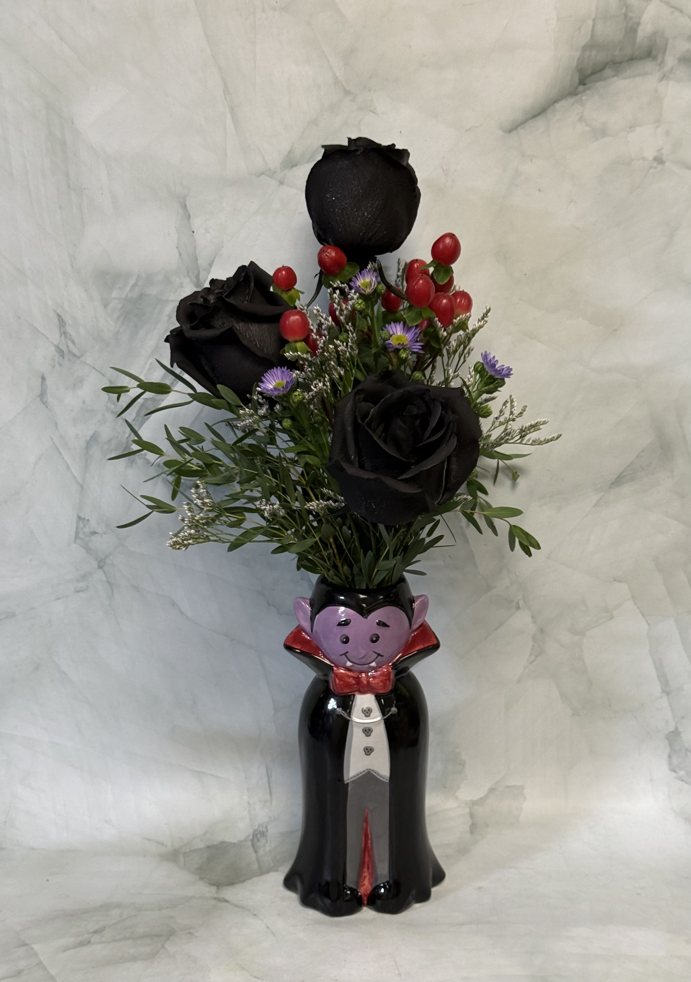 Vampire Kisses - This adorable Count Dracula budvase is the hot item this Halloween. This is a keepsake vase that is shaped like Count Dracula himself. Send them something spooky this Halloween season. The arrangement includes black Roses, red berries, Aster, and Limonium. 