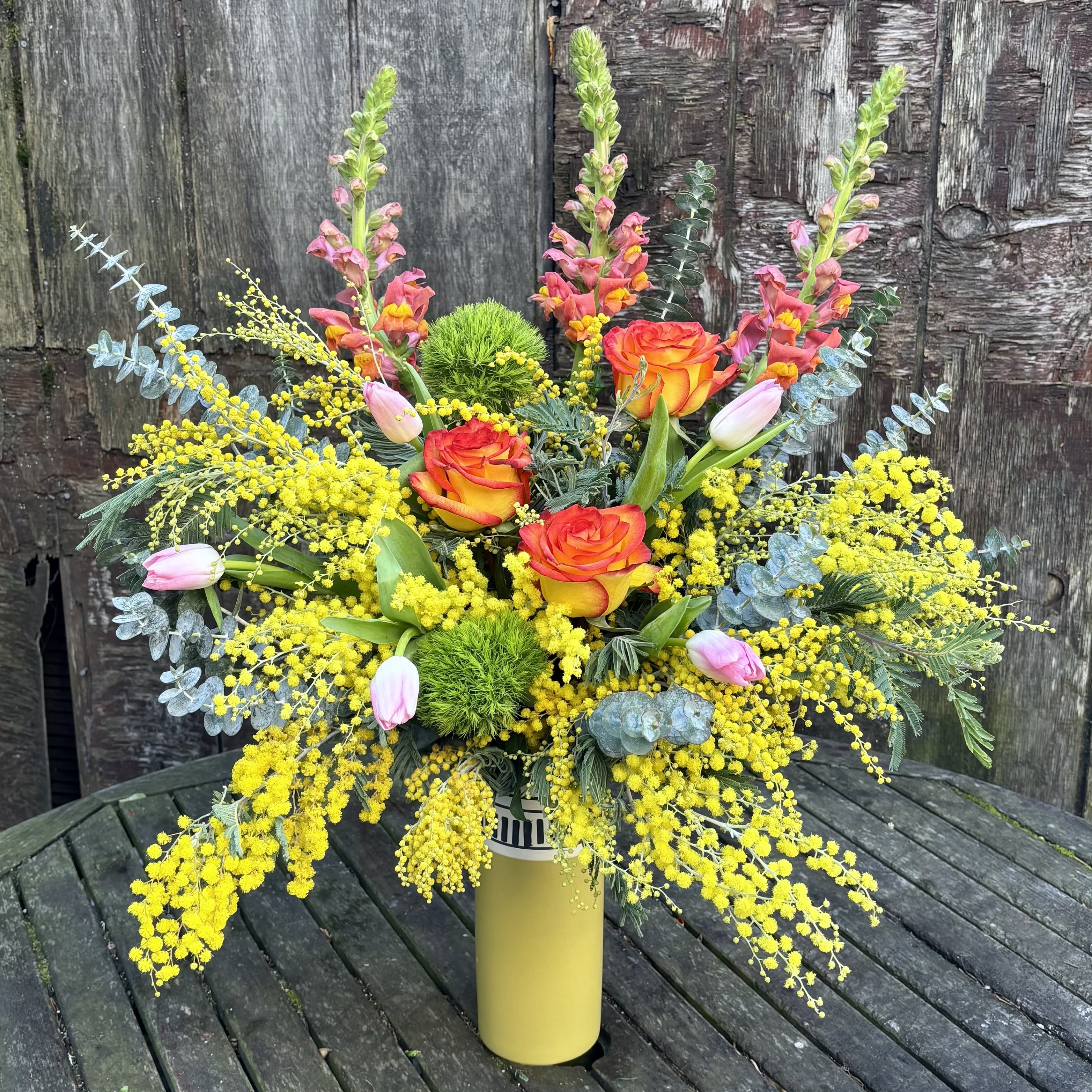 Mimosas in the Mornings  - Mimosa is only available a few weeks a year. And when it's finally here, it sure knows how to make an entrance. Fragrant and vibrant, these bright yellow flowers are sure to make its impact in any arrangement. Order Mimosas in the Mornings to lighten up your space. Light pink tulips, High Magic roses, and orange snapdragons marry symbiotically to create an arrangement that lifts your spirits and freshen your space.  This design is only available for the short Mimosa season. Mimosa flowers symbolize strength, sensibility, and solidarity, especially on International Women's Day, March 8th. Its delicate, sunny-yellow blooms and ability to thrive in harsh conditions make it a powerful symbol for perseverance, hope, and the arrival of spring.