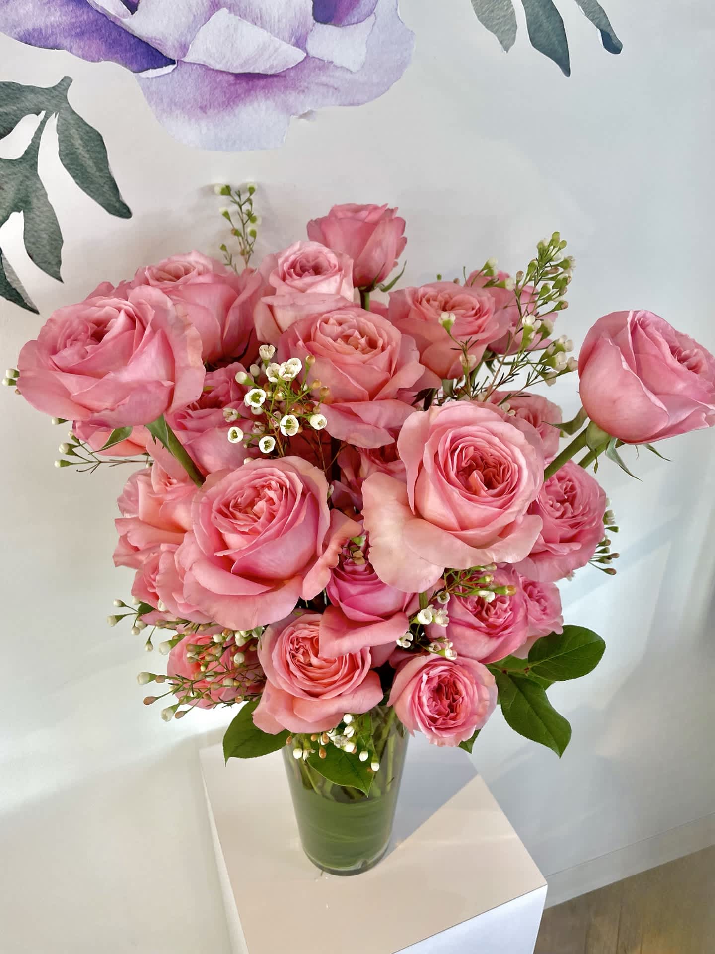 Roses in Pink!  - A rose is never just a rose.  We use premium gorgeous pink roses in a medium pink shade and vase them classic style.  A hit of wax flower or a local little flower or green may appear.  We offer this online by the dozen (standard) + 2 dozen vased size (deluxe).  It comes in a taller vase.  If you would like this shorter please let us know and we will gladly accommodate.  Its a beautifully striking arrangement just happy and pinky!  Photo shown is premium size.  