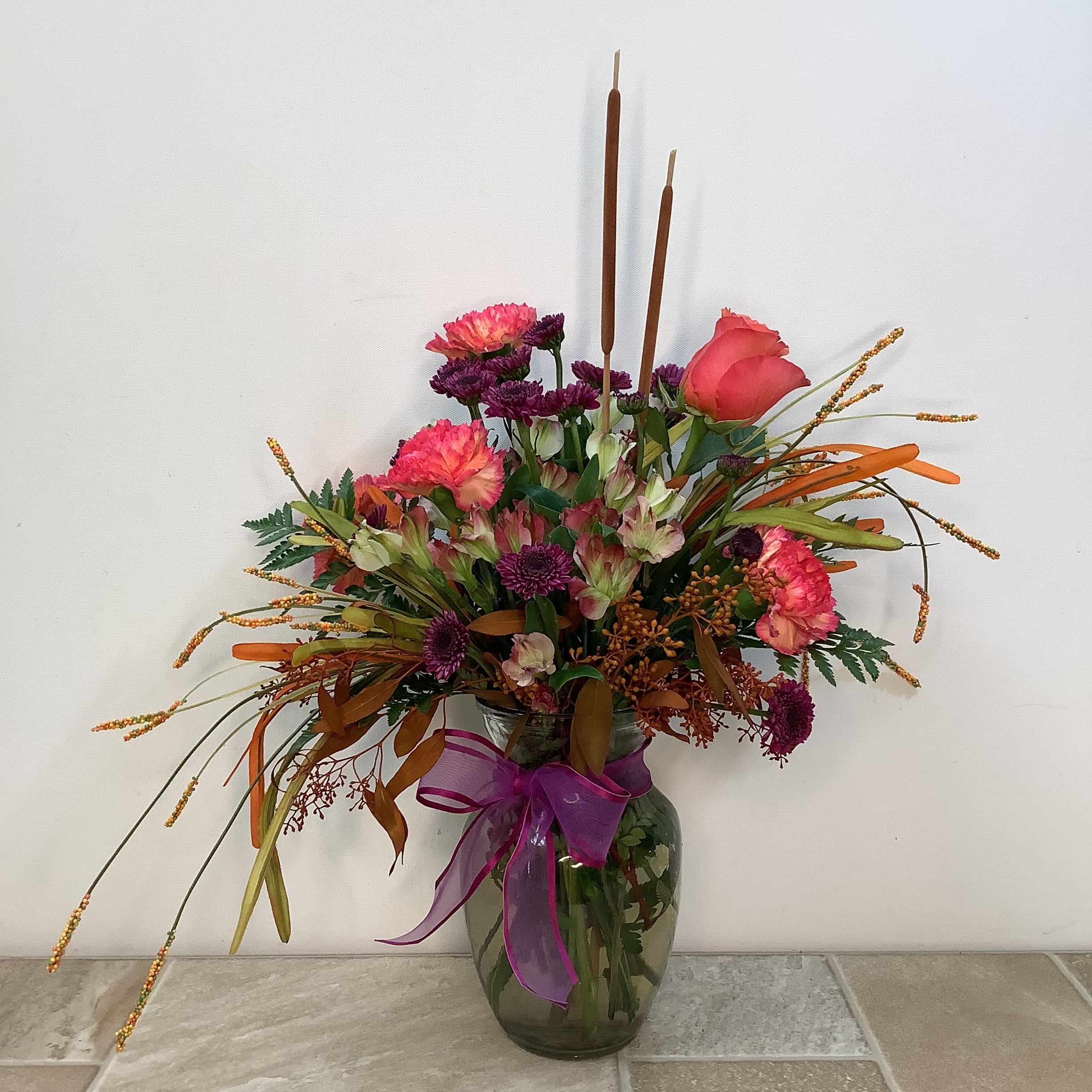 Fall Medley Fall Medley - Deep rich colors make our Fall Medley bouquet a really beauty. It includes jelly bean 2-tone carnations, charmelia, purple button poms and a cherry brandy rose. We’ve accented the arrangement with cattails, grasses and burnet orange seeded eucalyptus.