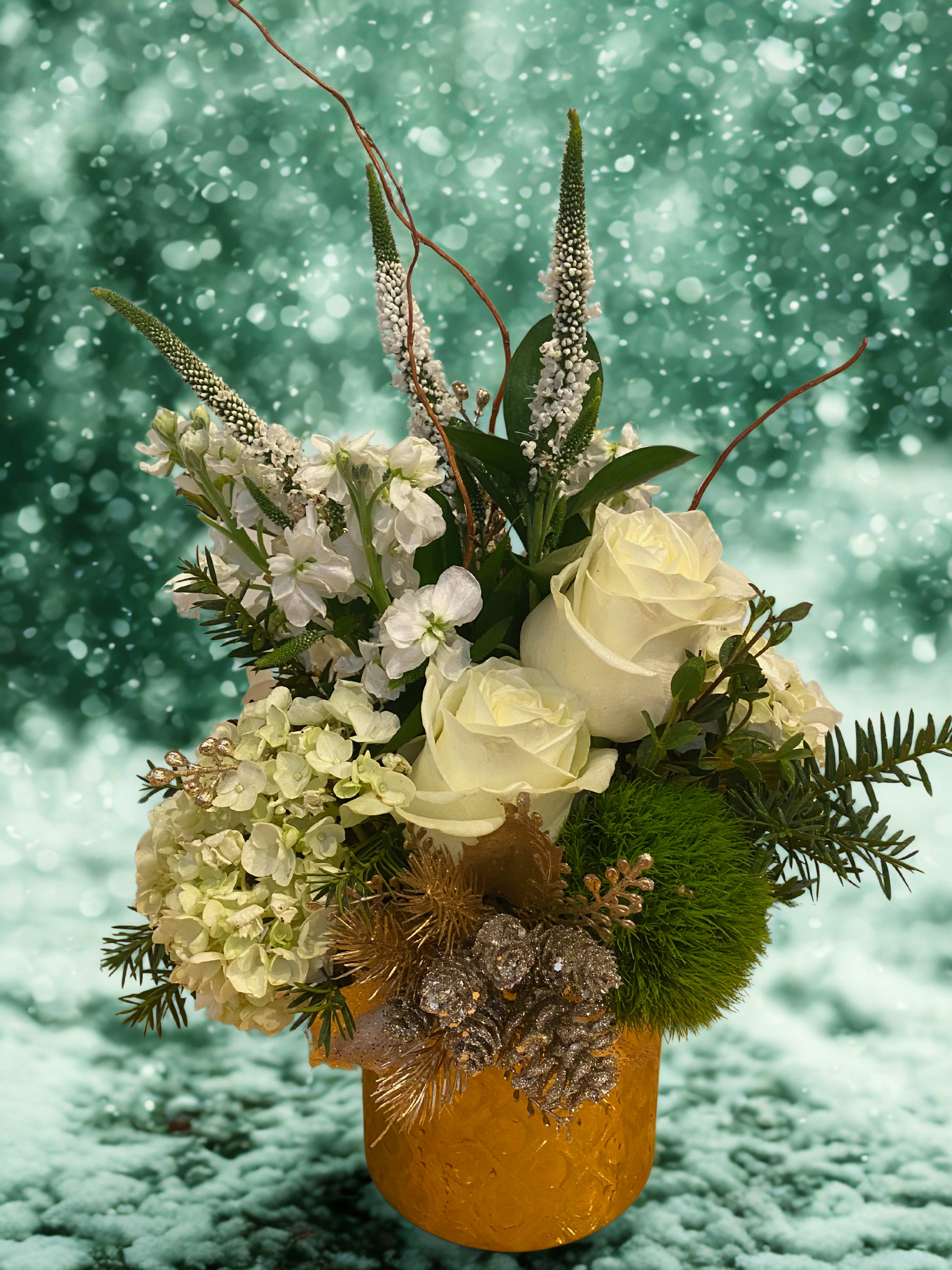 Gold and White - Gold patterned ceramic container filled with the freshest flowers for the holiday season. White roses, white stock, white veronica, green trick dianthus, white hydrangea, pine greens and eucalyptus. Arranged delicately for the perfect holiday centerpiece. Includes artificial gold sprigs and a gold pinecone mix cluster accent. 