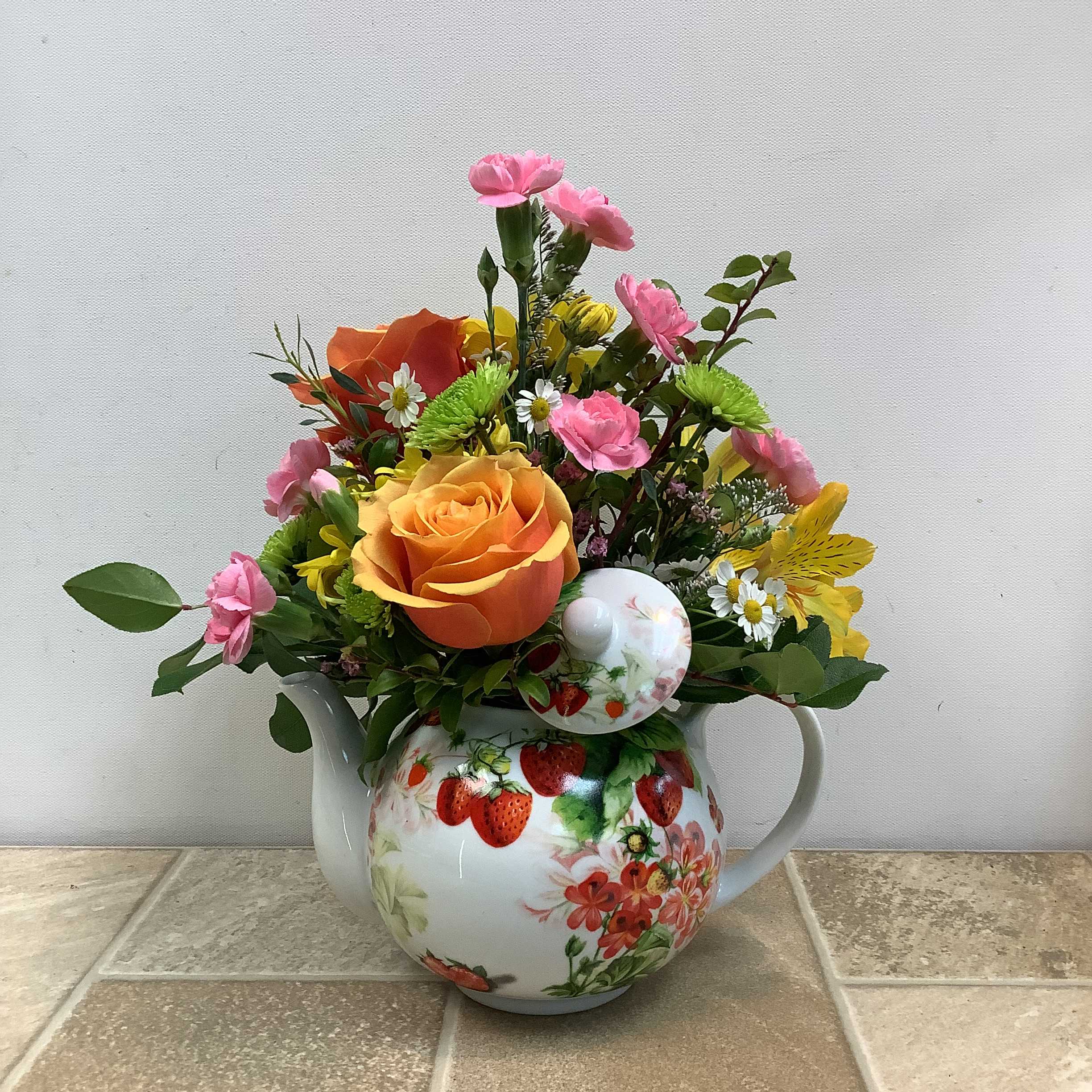 Strawberry Teapot Strawberry Teapot - A lovely bouquet inspired by one of the prettiest ceramic teapots you’ll find. We’ve filled it with fresh roses, alstroemeria, mini carnations, daisies and feverfew. It measures 11” wide x 12” tall.