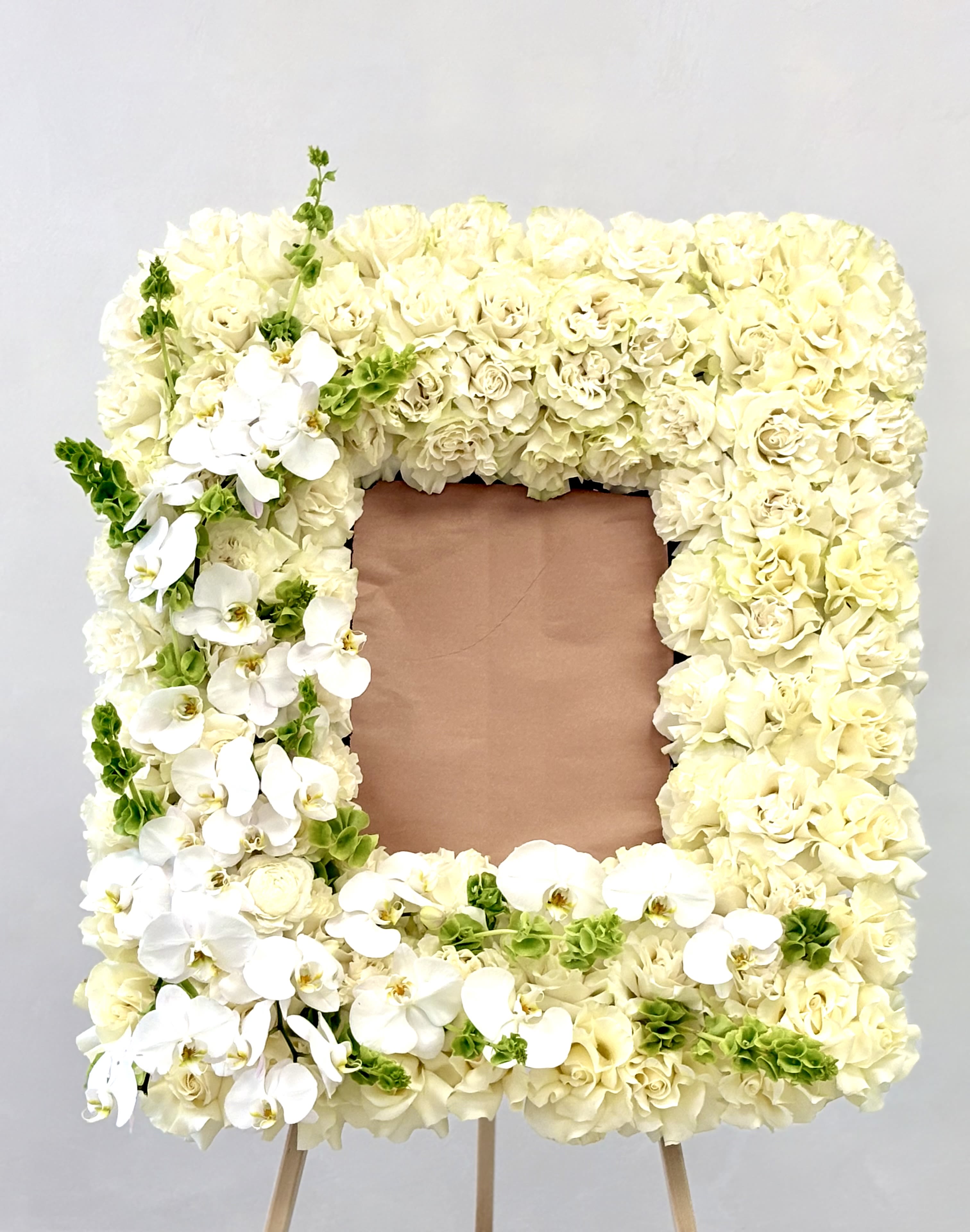 White Serenity By VLM Flowers White Serenity By VLM Flowers - A graceful frame of white roses and cascading orchids symbolizes peace, purity, and eternal remembrance.
