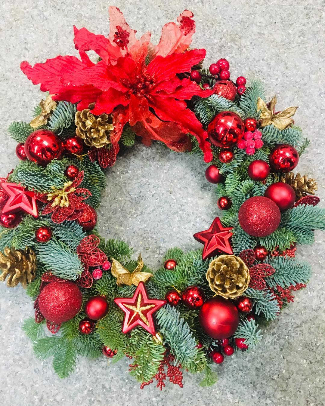 Christmas Wreath  Christmas Wreath  - The fen consists of green spruce branches decorated with red poinsettia flowers, red berries, red balls, gold cones, and red stars.