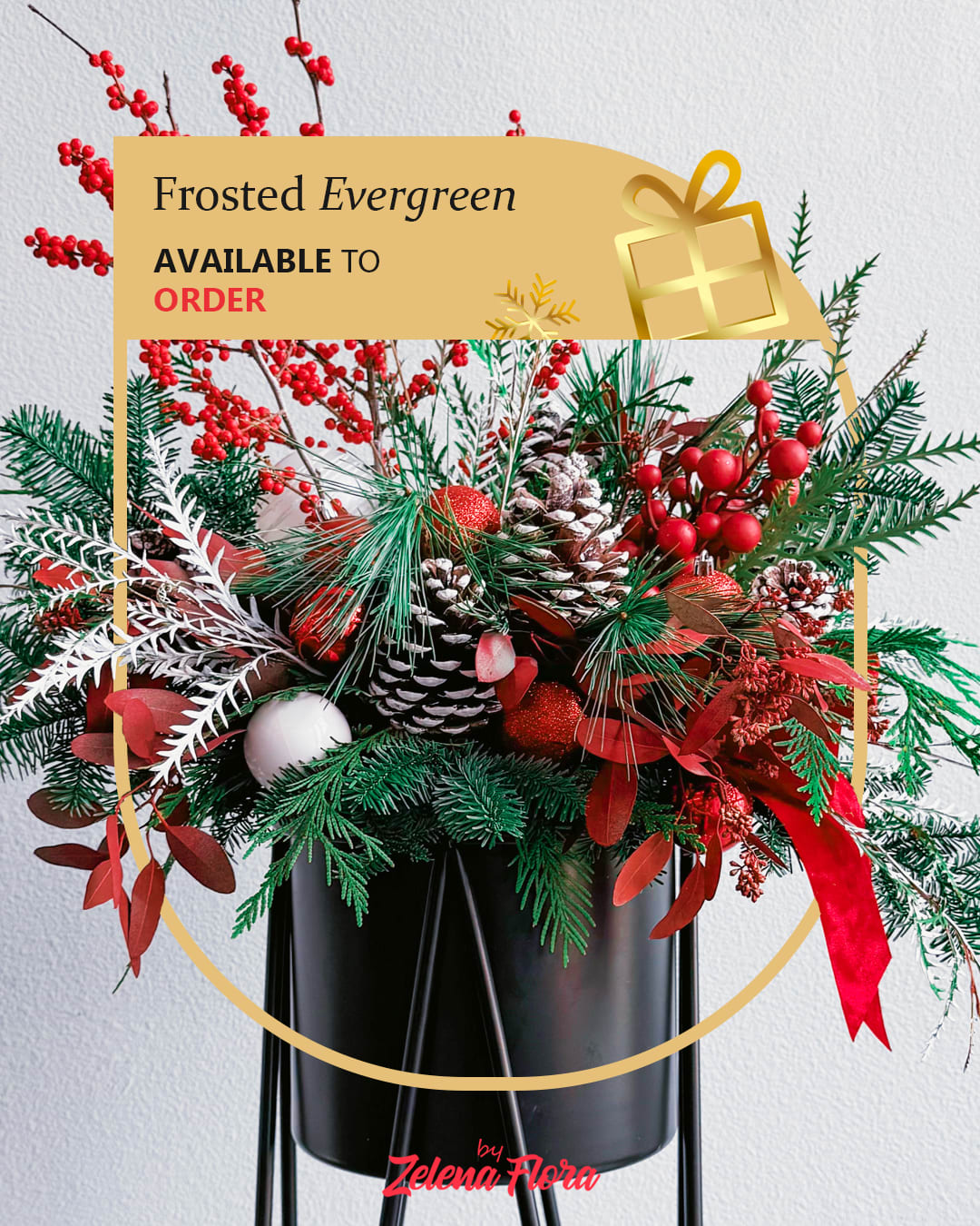 Frosted Evergreen Frosted Evergreen - This breathtaking Christmas bouquet captures the essence of winter festivities with its vibrant red berries, frosted pinecones, and lush green branches. Delicate white and silver accents, paired with shimmering ornaments, create a snowy, magical atmosphere. The arrangement is elegantly presented in a sleek black vase, adding a touch of modern sophistication to its traditional holiday charm.  Elements and Decorations: Natural components: Fresh fir and pine branches, red winter berries, and eucalyptus leaves (painted red and white). Decorative items: Frosted pinecones, red and silver baubles, and shimmering white ornaments.