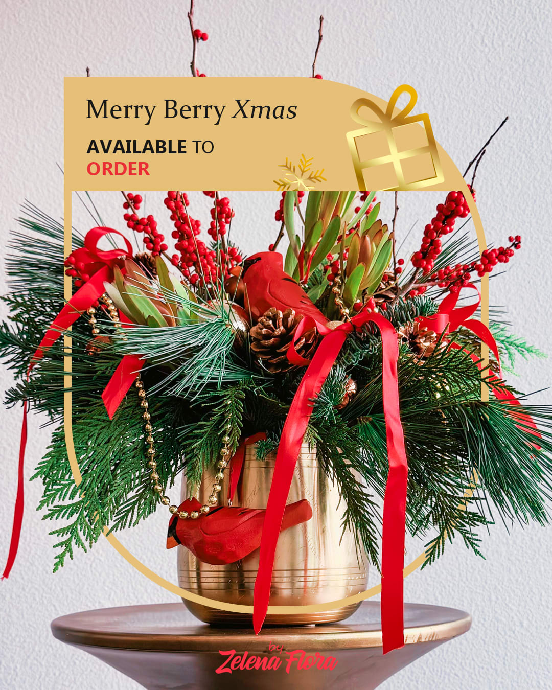 Merry Berry Xmas Merry Berry Xmas - This Christmas bouquet radiates festive warmth and charm, combining vibrant red and lush green tones with golden accents. Fresh evergreen branches create a foundation for clusters of red berries, golden pinecones, and delicate ribbons. The centerpiece features a bright red cardinal ornament, symbolizing hope and holiday joy. The arrangement sits in a golden vase, bringing a touch of elegance and sparkle to any celebration.  Elements and Decorations: Natural components: Fresh fir and pine branches, red berries, and leucadendron leaves. Decorative items: Pinecones (natural and gold), glossy ornaments, a red cardinal figurine, and flowing red ribbons. Container: Metallic gold vase.