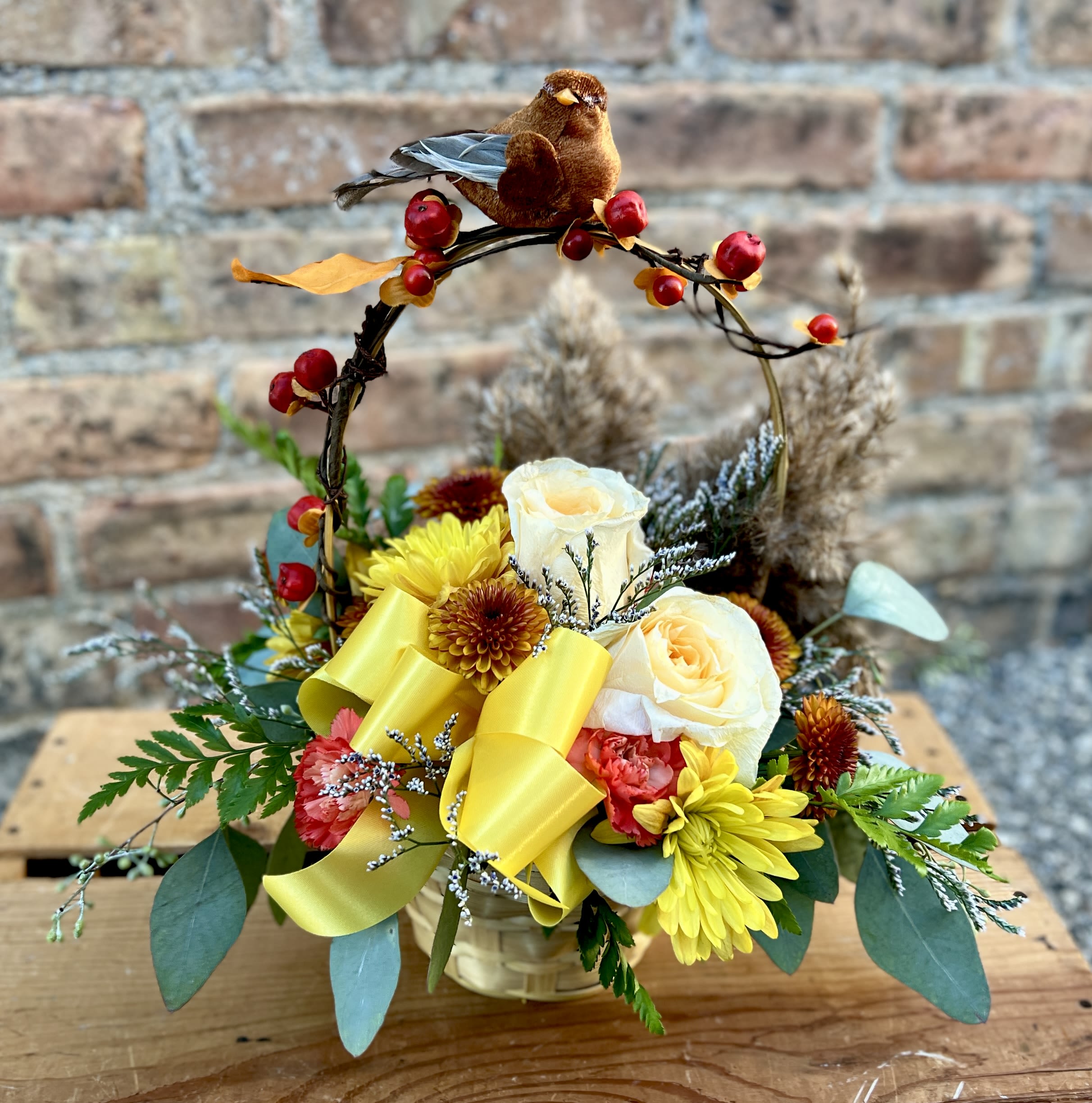 Fall Bird Song - This basket is filled with fall mums, mini carnations, roses, filler, grasses, and greens. A beautiful bird perches on the handle. Approx. 13&quot; H x 16&quot; W  We are proud to deliver our flower creations to the Kenosha, Somers, and Pleasant Prairie area. With over 55 years of combined flower design experience in Kenosha, Wisconsin, A Summer's Garden Florist and Gifts is the perfect choice for the freshest flowers, the most creative design, and exceptional customer service.