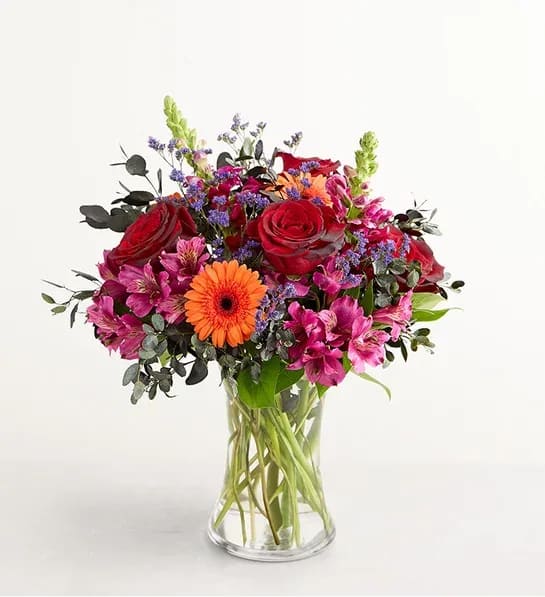 Spooky Sensations - Spooky meets sensational! Our Halloween-themed arrangement features a mix of orange and purple blooms, with black-tinted roses and foliage for an enchanting touch. Hand-gathered into a striking crescent shape, this “boo-tiful” bouquet captures all the magic this time of year brings.  One-sided crescent-shape arrangement with mini orange Gerbera daisies, purple Peruvian lilies (alstroemerias) and limoniums, and red roses tinted black, accented with assorted black-tinted greenery Artistically designed in a clear glass vase; measures 8&quot;H Large arrangement measures approximately 18&quot;H x 19&quot;W Medium arrangement measures approximately 17&quot;H x 18&quot;W Small arrangement measures approximately 16&quot;H x 17”W We hand-design each arrangement, so colors, varieties, and container may vary due to availability To ensure lasting beauty, Peruvian lilies may arrive in bud form and will fully bloom over the next few days