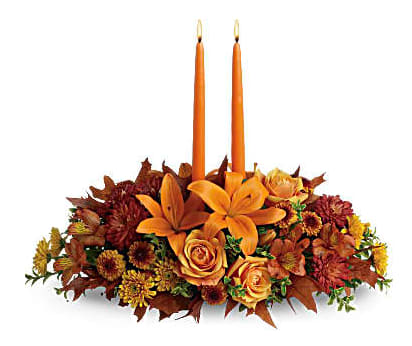 Family Gather Piece Family Gather Piece - Graciously gather your family around the warm glow and classic autumn colors of this stunning Thanksgiving centerpiece. A lush variety of burnt orange blooms are gathered under a pair of tall, graceful candles - perfect for decorating your Thanksgiving dinner table, entryway or hearth. Fall flowers include orange roses, orange asiatic lilies, dark orange alstroemeria, bronze button mums, yellow cushion mums, rust cushion mums, green oregonia and green huckleberry. Accented with oak leaves and two orange taper candles. Orientation: All-Around