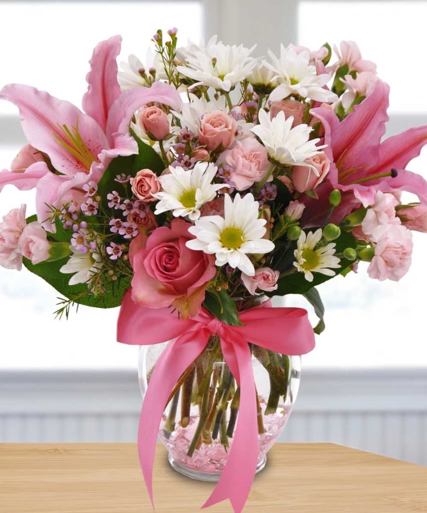 Happy Days - Breast Cancer Awareness Month Happy Days - Breast Cancer Awareness Month - Our delightful Happy Days arrangement is sure to make people smile. This is a fun and flirty combination of pink lilies, roses, carnations, and wax flowers with cheerful white daisies, Hypericum berries, and other accents just ooze happiness. We dress it up with a big bright satin pink ribbon.
