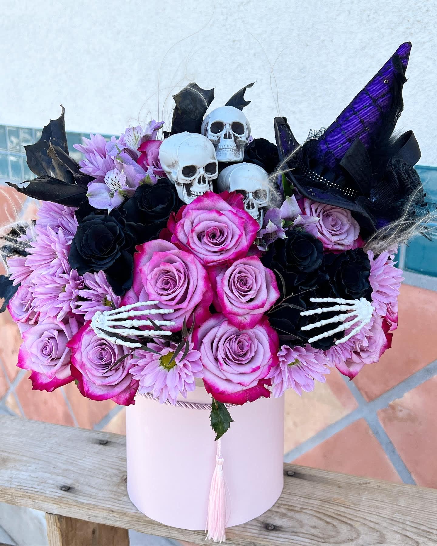 Witchy witch bouquet - Cast a floral spell this Halloween with a bewitching mix of deep purple and black blooms, artfully arranged and topped with a classic witch hat. Mysterious, magical, and full of Halloween charm — it's the perfect touch of spooky elegance for any haunted celebration.