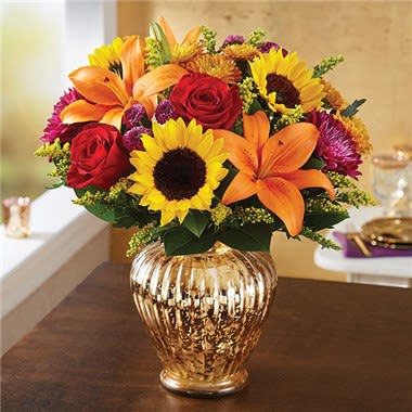 AUTUMN BRILLIANCE - EXCLUSIVE Our brilliant new arrangement was designed to delight! Beautifully hand-created by our expert florists, each fall-toned bloom is highlighted by our shimmering gold mercury vase. Whatever sentiment you’re trying to capture, this warm and wonderful surprise is one they won’t soon forget. •All-around arrangement with red roses; orange Asiatic lilies; sunflowers; bronze cushion poms; purple mums and button poms; accented with solidago and salal •Artistically designed in our exclusive gold mercury vase; measures 8&quot;H •Arrangement measures approximately 16&quot;H x 10&quot;L •Our florists hand-design each arrangement, so colors and varieties may vary due to local availability •To ensure lasting beauty, lilies may arrive in bud form, and will fully bloom over the next few days