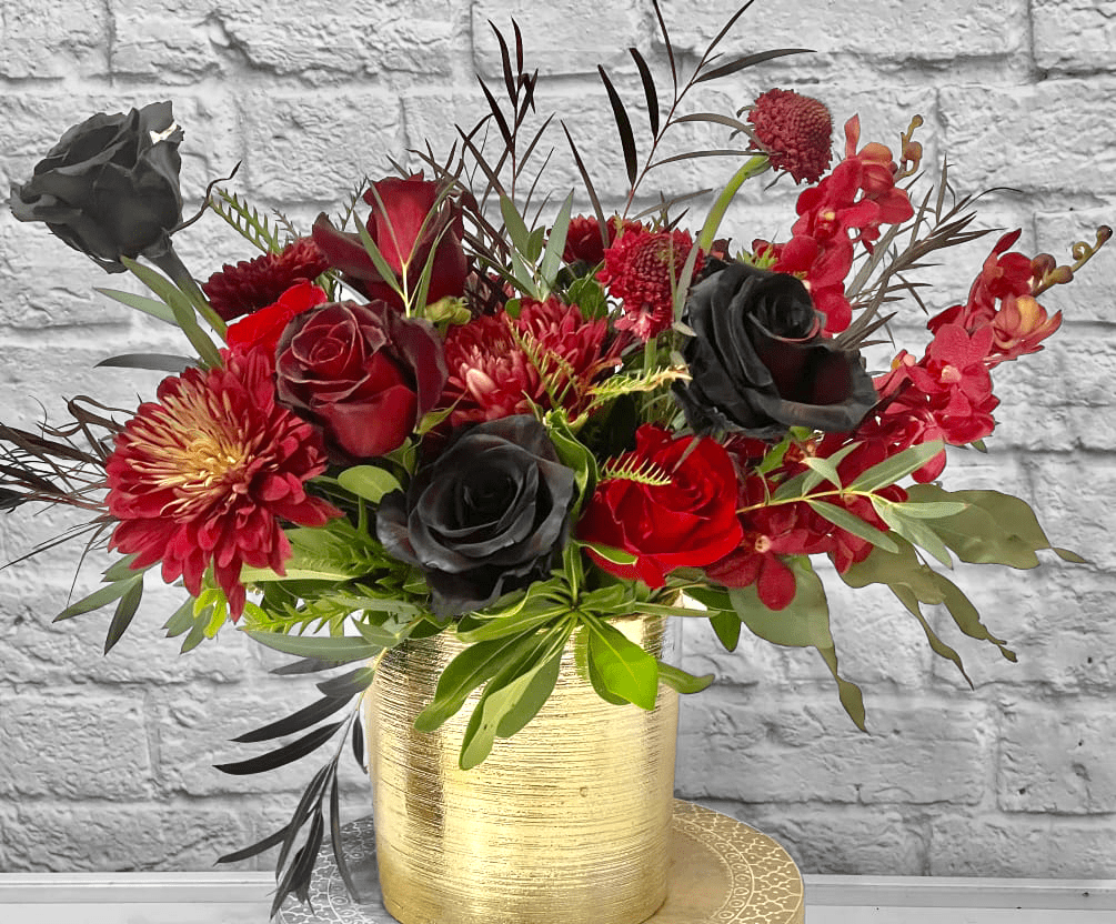 Morticia Morticia - Black roses, black Baccara roses (dark red with black edges), orange roses, Chinese lanterns, dried Mushrooms all enhanced with dark foliage and pods.