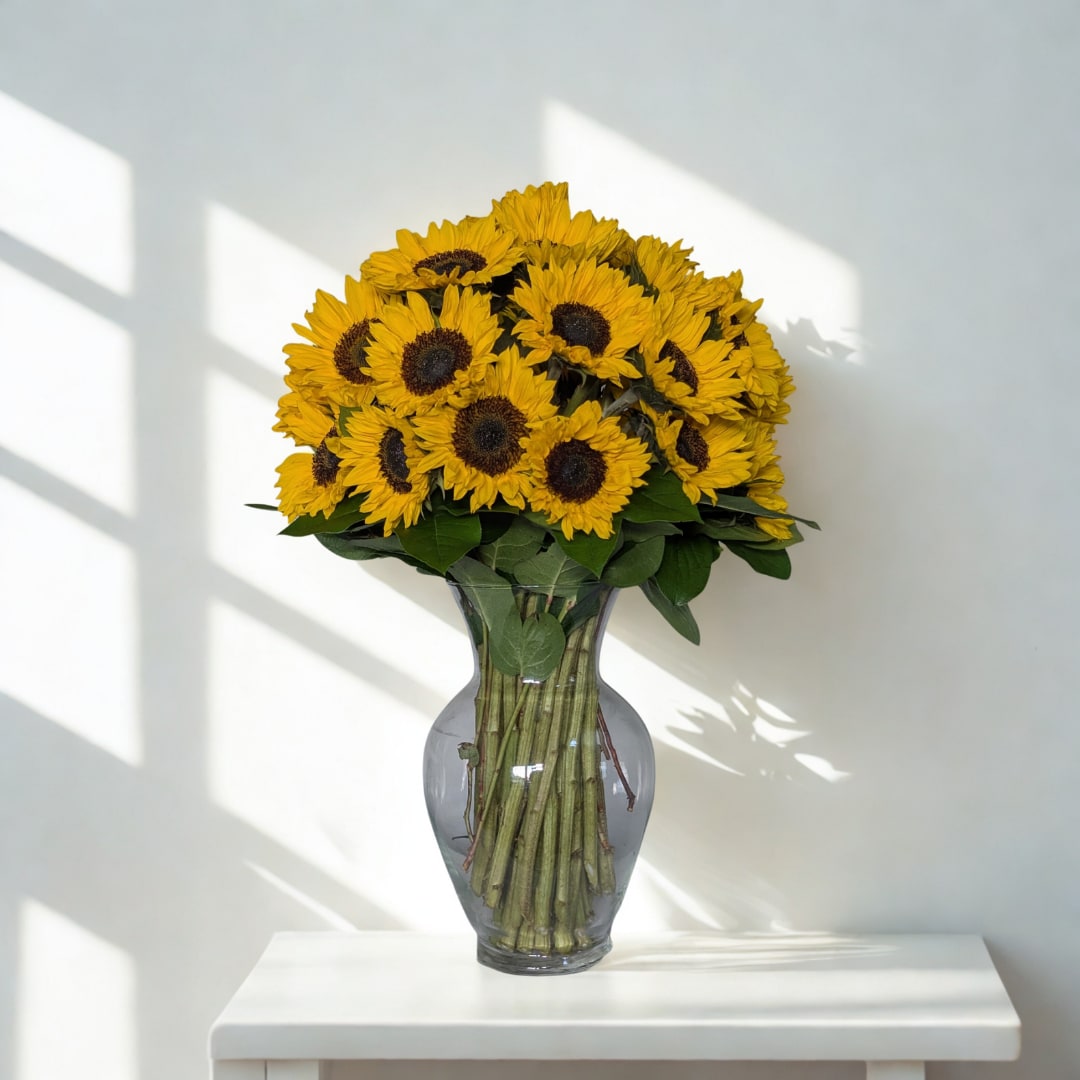 Sunny Elegance - A radiant gathering of golden sunflowers, arranged simply and beautifully in a clear hourglass vase. This design highlights the natural charm of sunflowers, perfect for brightening any room with joy and sunshine.