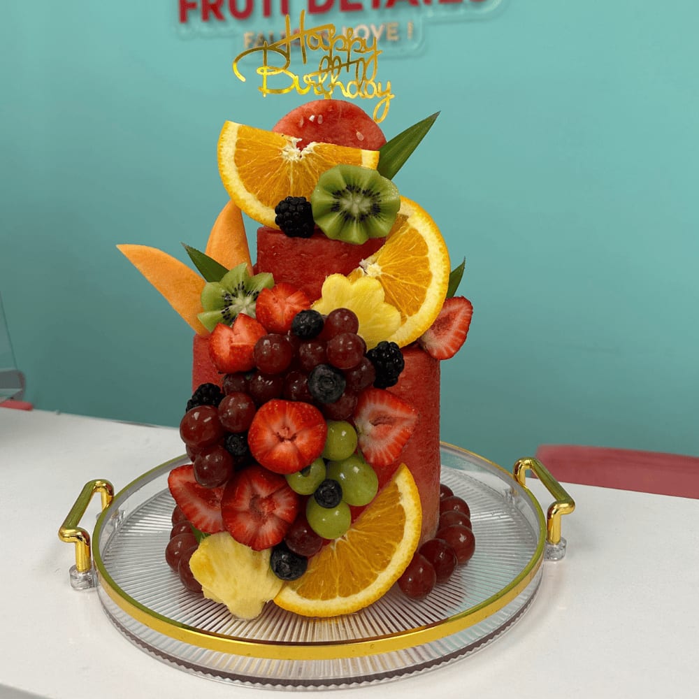 Birthday Fruit Watermelon Cake - Happy Birthday fruit Cake– Fruit cakes for birthday Send smile to Celebrate birthday with Fruit Cake, ours fruit tart is elegant gifts with Delivery from Miami springs fl. we offer send the Fruit Cake for Same day delivery in less than 4 hours, unforgettable with this stunning, 100% edible fruit &quot;cake&quot; – a healthy and vibrant alternative to traditional sweets.  This arrangement includes:   Two layers of carved fresh watermelon as the cake base  Topped and decorated with strawberries, red and green grapes, blueberries, blackberries, kiwi, cantaloupe, pineapple flowers, and orange slices  Accented with tropical greenery for an elegant look  Acrylic golden &quot;Happy Birthday&quot; topper  Protected with a clear acrylic cover, finished with a decorative ribbon and bow  Presented on a premium round acrylic tray with gold handles – sturdy and beautiful  Perfect for:  Healthy Happy birthday celebrations with Fresh Fruit,  Fruit lovers and elegant party tables, Gift deliveries across Miami, FL and surrounding areas.