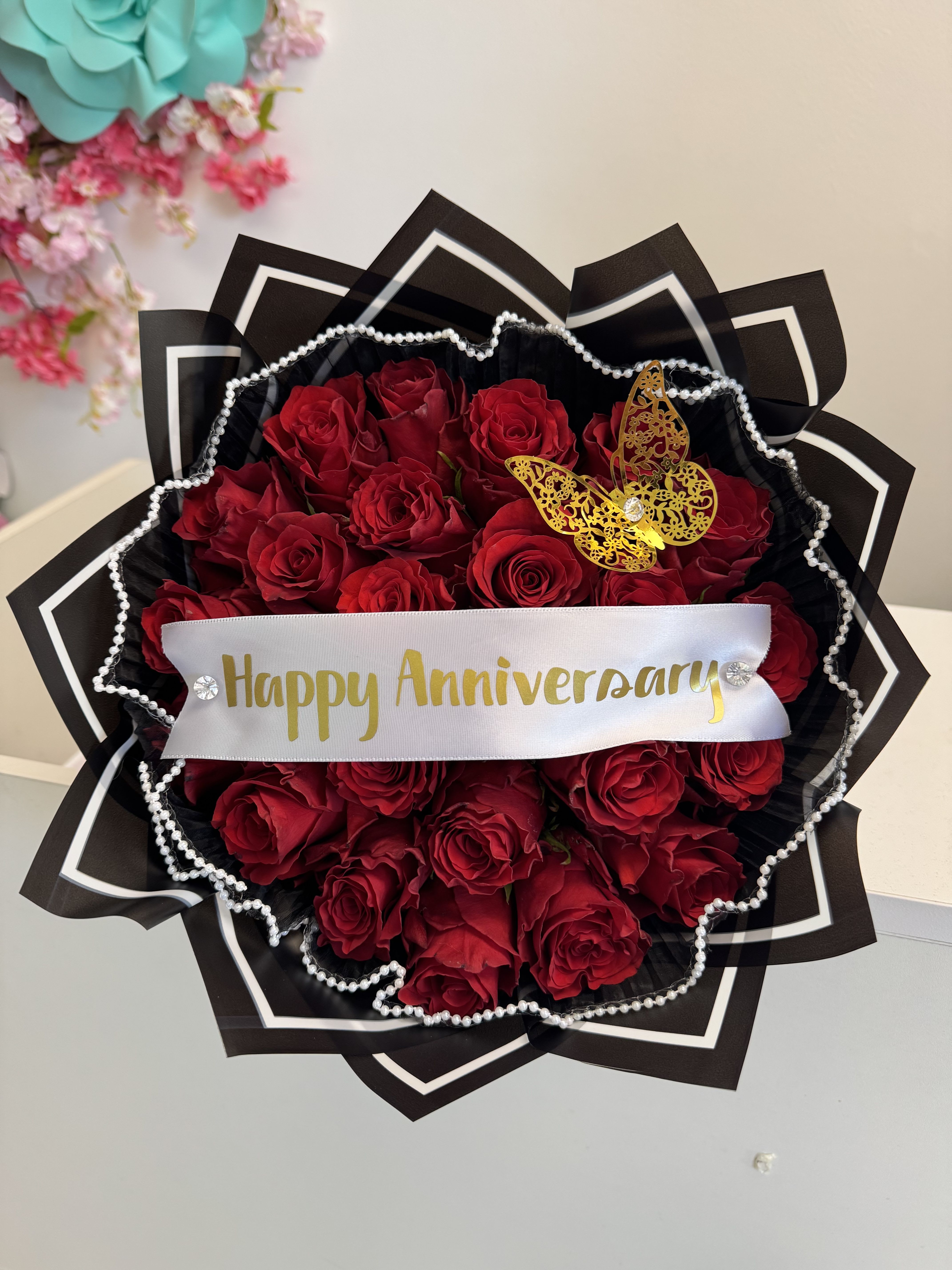 Express Your Love with 25 or 50 Red Roses – Anniversary Bouquets in Miami - ️ Red Rose Bouquet with Crown – Anniversary Gift A romantic and luxurious gift for your partner. This stunning red rose bouquet is crowned with a decorative gold tiara, golden butterfly, and a satin ribbon printed with “Happy Anniversary” (also available in Spanish: “Feliz Aniversario”), making it perfect for celebrating love and lasting memories.  Available in three sizes:  25 roses – sweet and meaningful  50 roses – impressive and full  75 roses – the ultimate romantic gesture  Includes:   Fresh red roses (choose 25, 50, or 75 stems)  Gold crown with pearls (decorative accent)  Metallic gold butterfly  Satin ribbon with Happy Anniversary or Feliz Aniversario  Wrapped in elegant pink paper with pearl trim  Ready-to-gift presentation  Local delivery available in Miami Springs and surrounding areas  Perfect for:   Anniversary celebrations ️ Romantic surprises  Declaring lasting love in a grand way  