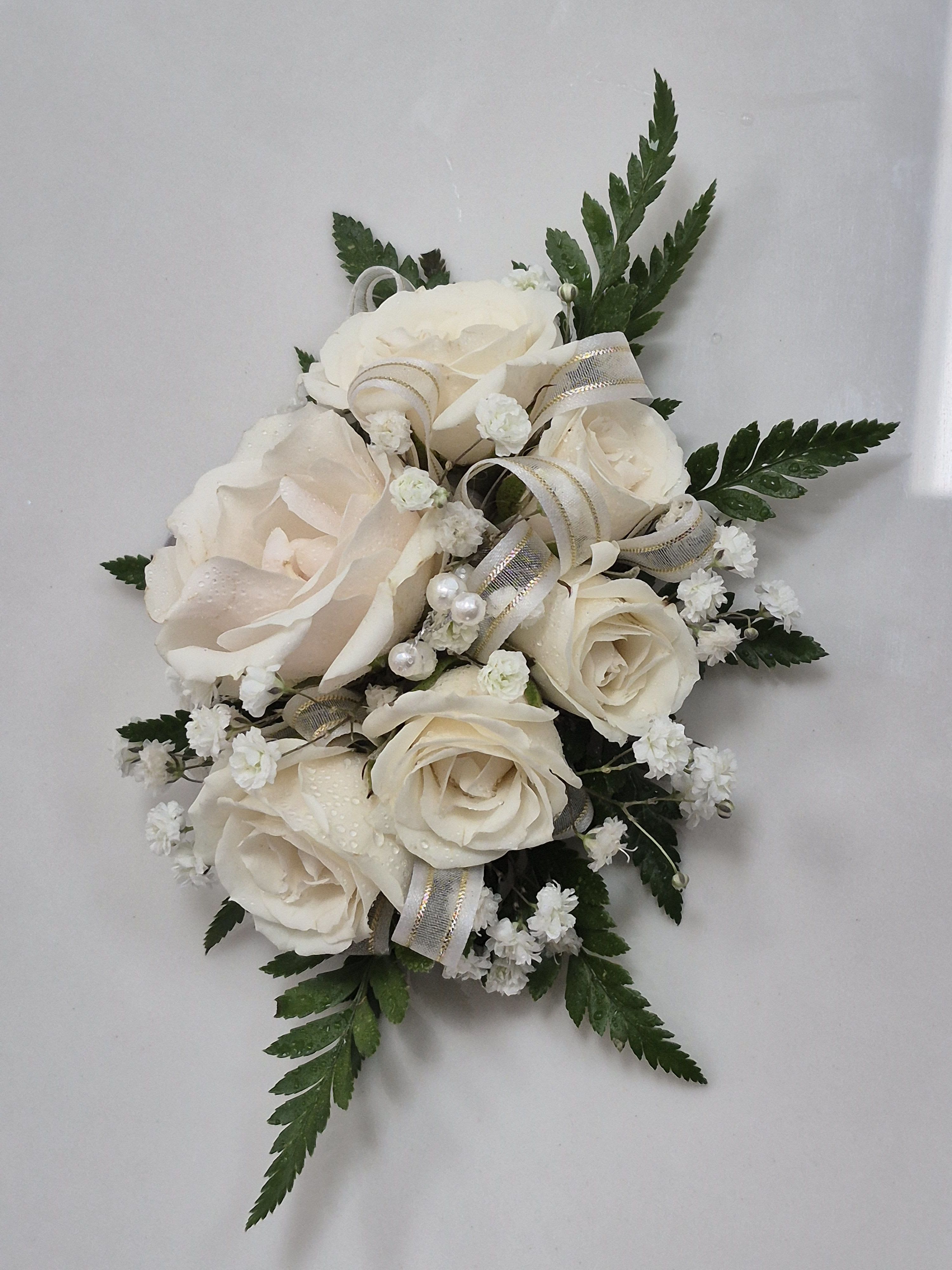 Cream Corsage Cream Corsage - Prom flower ideas : beautiful cream garden rose wrist corsage, boutonniere and petite handheld bouquet for prom. All designs are completed with a lovely matching purple chiffon ribbon. Order as a set or individually. Professionally designed perfect prom flowers or wedding flowers. Beautiful wrist corsage for prom and wedding. Pearly Girly prom corsage is 4 inches wide and 4 inches high with garden roses, white babies breath, pears and comes with a stretchy elastic wrist band. Upgrade the wristband to a prom corsage bracelet for $10 more: rhinestone or pearl bracelet option Purple prom bouquet is 6-7 inches across with 9 mini cream roses, white babies breath and 6 pearls. Purple prom boutonniere is 3 inches wide and 3 inches long with 1cream rose bud, white babies breath and 1 pearl stem. Includes a pearl head pin to attach the mens boutonniere to his suit lapel.