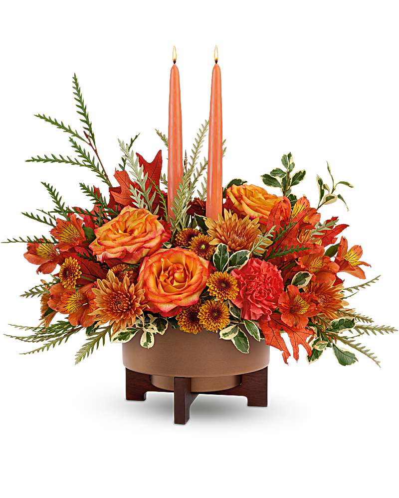 Fall Harvest Centerpiece - Warm hearts and tables with The Fall Harvest Centerpiece. Featuring two elegant taper candles and a rich mix of orange blooms, this stunning arrangement shines in The Modern Copper Planter. A perfect fit for Thanksgiving or any occasion this autumn The Fall Harvest Centerpiece includes orange bi-color roses, orange alstroemeria, orange carnations, orange button spray chrysanthemums, and rust cushion spray chrysanthemums. Accented with grevillea, oregonia, preserved oak leaves, and two peach candles in The Modern Copper planter