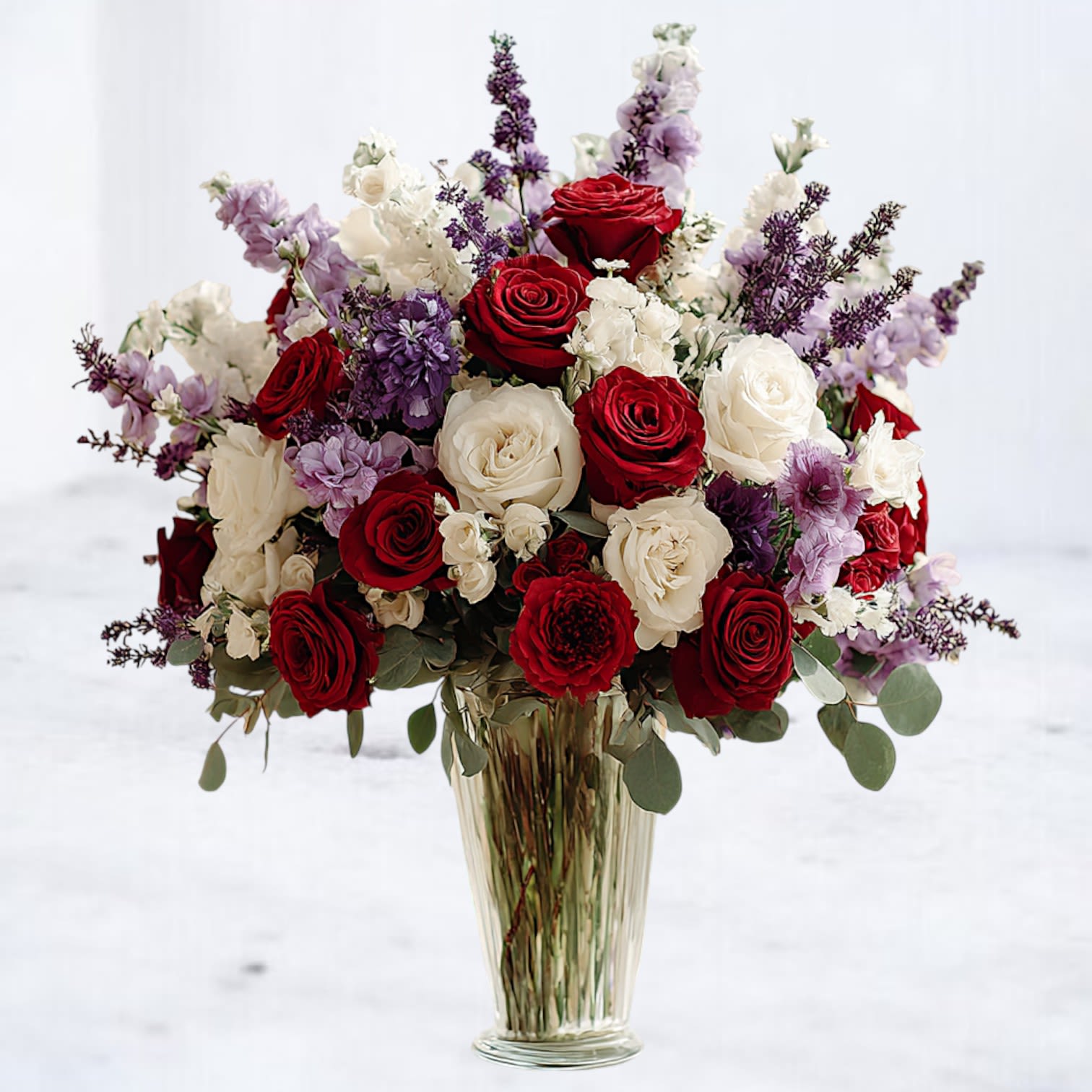Regal Harmony Regal Harmony - Regal Harmony is a lavish arrangement designed to impress. Featuring 18 velvety red & white roses, creamy ivory blooms, and delicate lavender stock, this tall glass vase bouquet radiates timeless beauty and sophistication. Perfect for anniversaries, heartfelt sympathy, or an unforgettable luxury gift, this arrangement blends bold romance with gentle elegance.