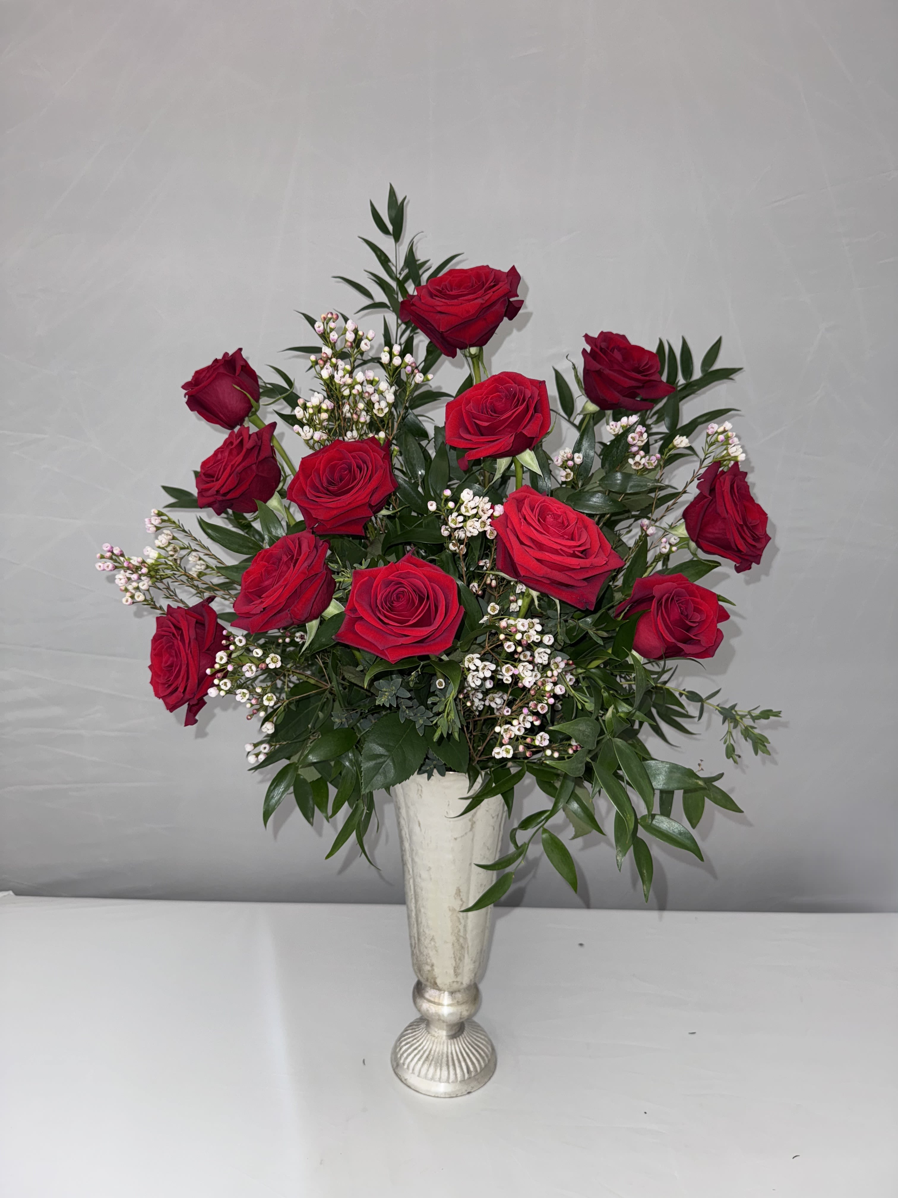 SOPHISTICATED LOVE  - 1 DOZEN LONGSTEM ROSES SOPHISTICATELY ARRANGED WITH PREMIUM GREENERY, ITALIAN RUSCUS AND EUCALYPTUS IN A METAL PEDESTAL LITA VASE FROM ACCENT DECOR. VASE IS 6.5WX14H.  DELUXE: 2 DOZEN ROSES 