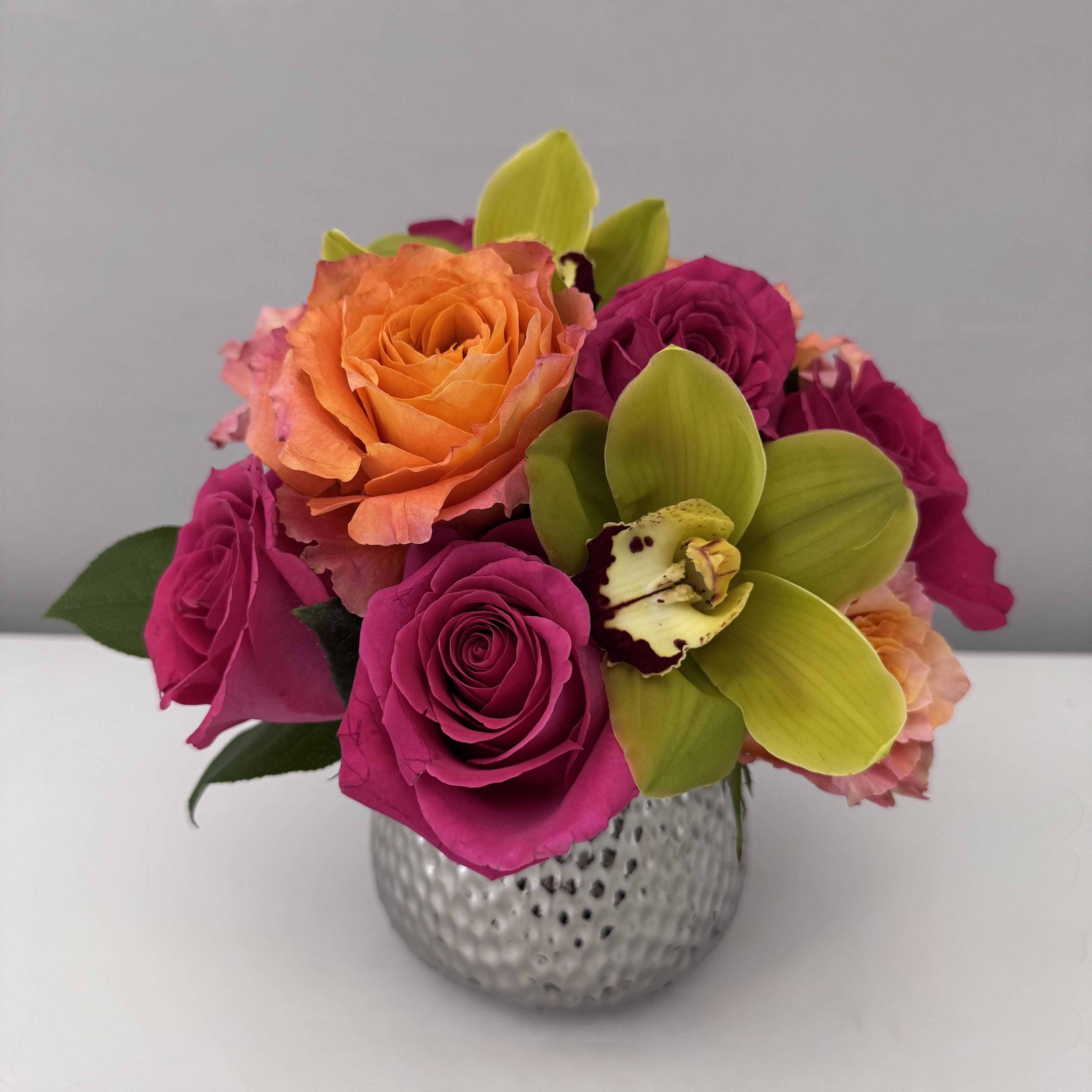 GOOD VIBES  GOOD VIBES  - A VIBRANT MIXTURE OF HOT PINK FLOYD & ORANGE FREE SPIRIT ROSES IN A PETITE TEXTURED SILVER POT.  CONTAINER IS 5WX4.5H.