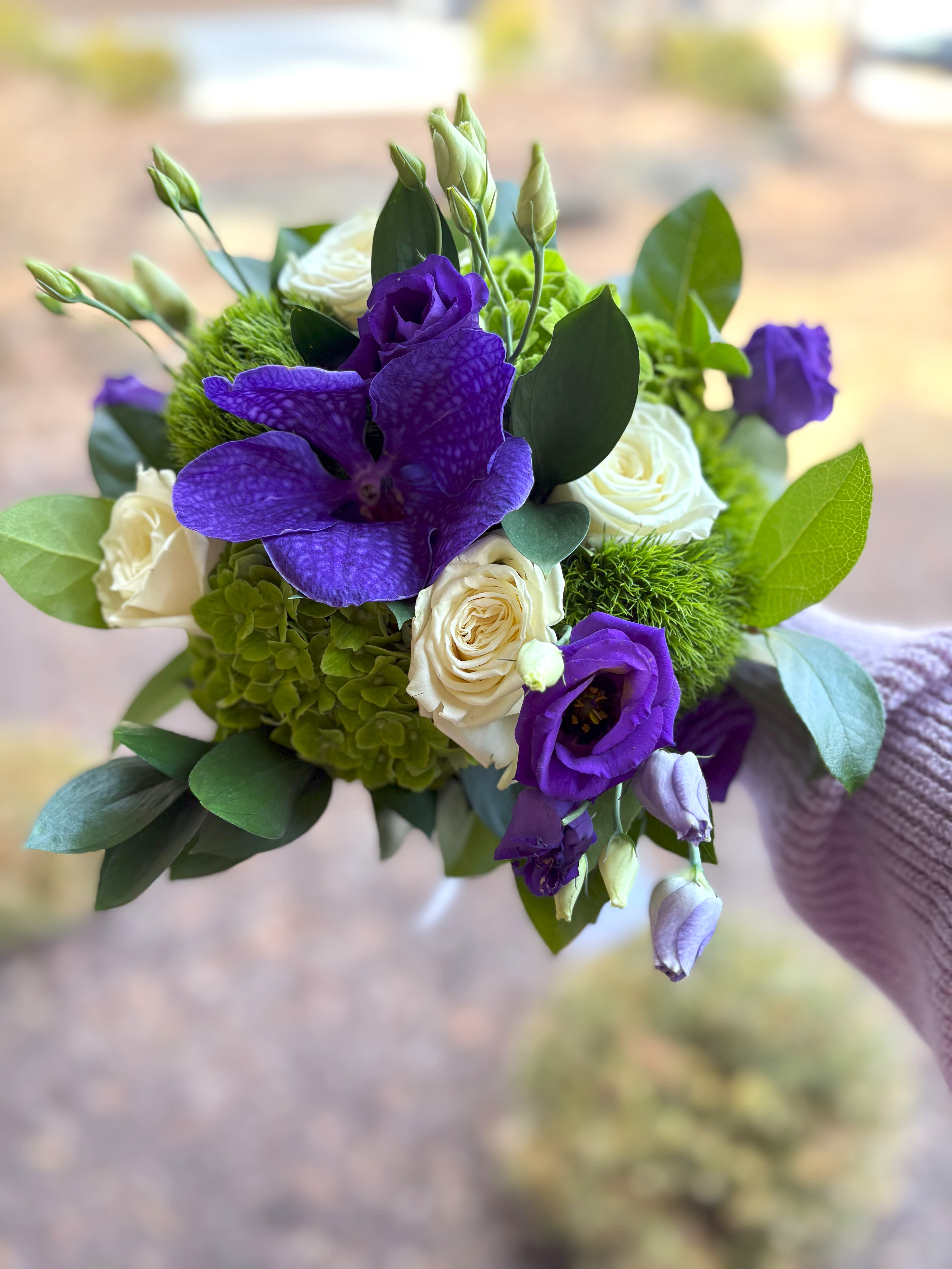Purple Passion Handheld Bouquet - Green hydrangea, purple lisanthus, white roses, green trick and a purple Vanda orchid round out this purple bouquet.  Tax free. Same day hand delivery.  We are a local florist in Wilmington, Delaware that provides the best delivery of fresh flowers on the same day. We also offer next day delivery. Our flower shop services the Wilmington and Newark Delaware areas as well as south eastern PA. We are a flower shop near you that is tax free and provides hand delivered flowers. We offer funeral, sympathy, anniversary, birthday, holiday, Mother's Day, Valentine's Day and rose arrangements and flowers for all occasions. Petals is a full service florist that offers the best online flowers and fresh flower arrangements. You can send flowers from our flower shop to Wilmington, New Castle, Newark, Hockessin, Chadds Ford, Kennett Square and other local cities near us.  