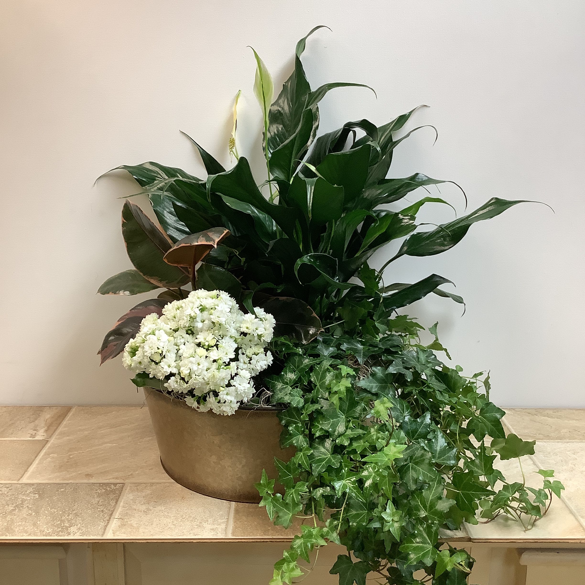 Green and blooming plants in 14” metal container Green and blooming plants in 14” metal container - A beautiful assortment of lush green plants and a seasonal blooming plant in a 14” metal container. It measures approximately 20” wide x 23” tall. NOTE: plants may differ from picture due to availability.