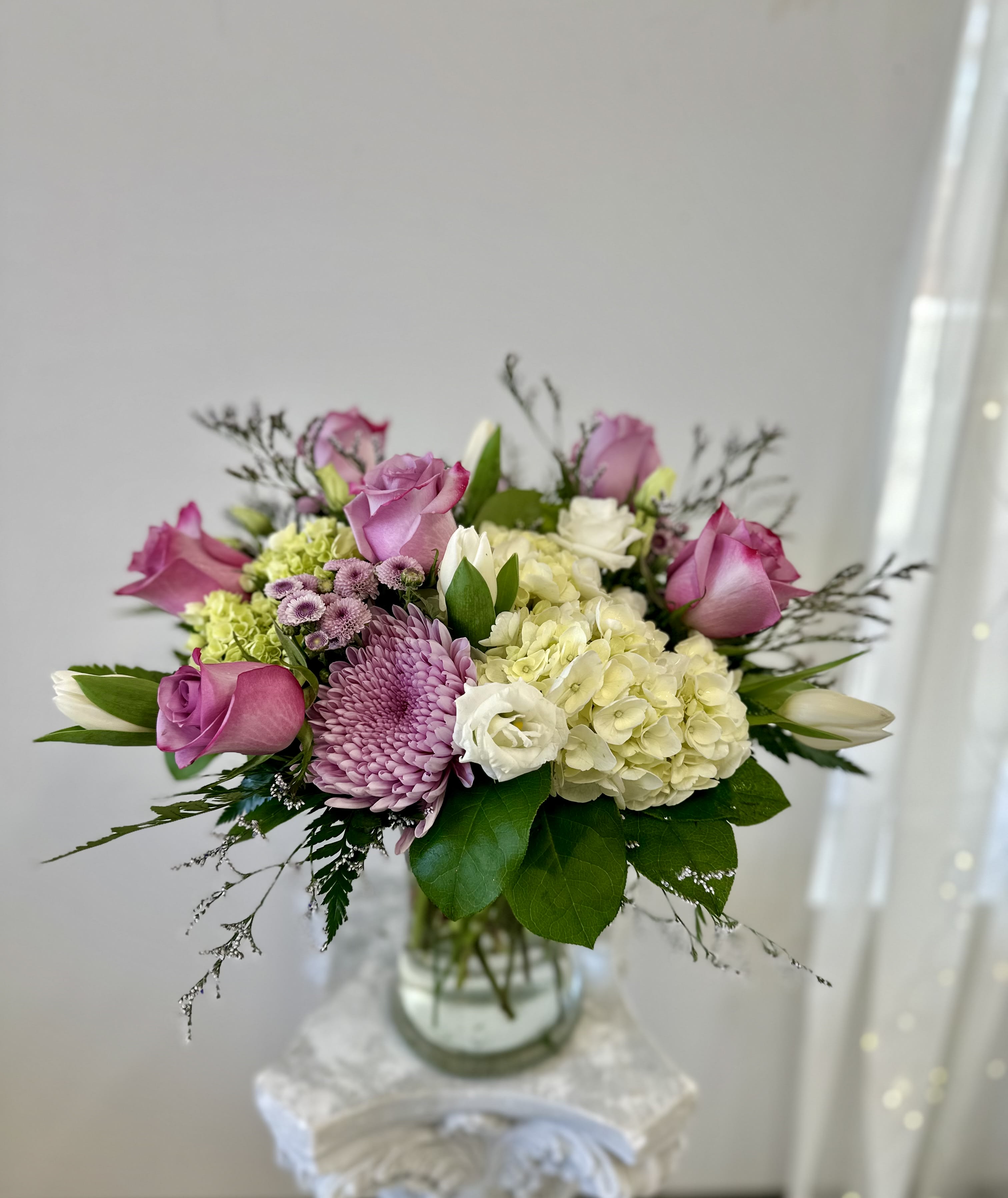 Lavender Delight by Westford Florist Art by Veny - Elevate your floral experience with the Lavender Delight arrangement by Westford Florist Art by Veny. This exquisite bouquet artfully combines lavender roses, hydrangeas, tulips, sea lavender, lisianthus, and an assortment of mums and poms to create a stunning visual symphony. Each bloom is thoughtfully selected to evoke a sense of elegance and serenity, making it an ideal gift for any occasion or as a luxurious indulgence for yourself. Allow the enchanting hues and delicate fragrances of this captivating arrangement to transform your space into a tranquil oasis of beauty. Experience the magic of nature’s artistry with Lavender Delight—where every stem tells a story of grace. Our expert florists take great care in selecting the finest, freshest flowers to create this stunning bouquet. The delicate balance of colors, textures, and scents is a testament to our commitment to providing our customers with the highest quality floral designs. So, get ready to have your senses dazzled by the Lavender Delight flower arrangement from Westford Florist – a true masterpiece that embodies beauty, romance, and nature’s splendor. Place your order today and experience the enchanting charm of this exquisite bouquet for yourself or someone special.