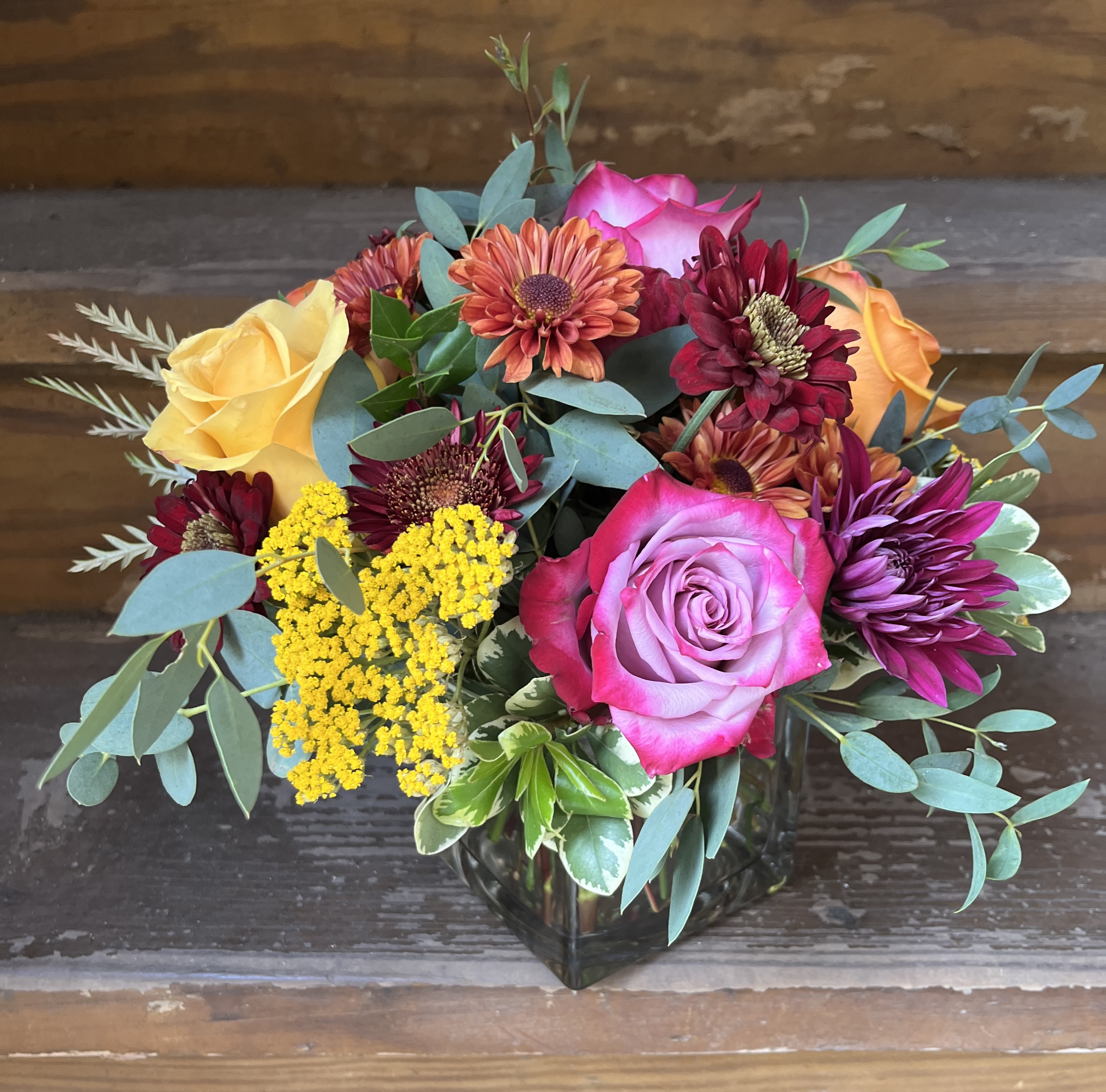 Fall Fiesta Fall Fiesta - Low arrangement of brightly colored florals of roses, fall mums, yarrow, accent florals and flowing greens.