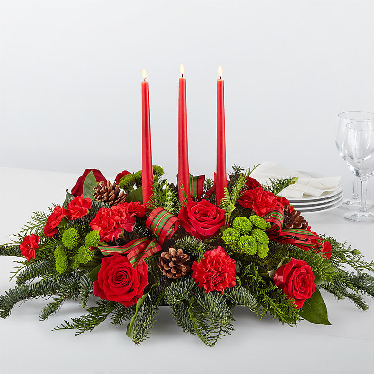 By the Candlelight Centerpiece - Let time fly By the Candlelight centerpiece as new holiday memories are made. What better way to commemorate the joyful homecoming than with classic red roses and lush evergreen accents?