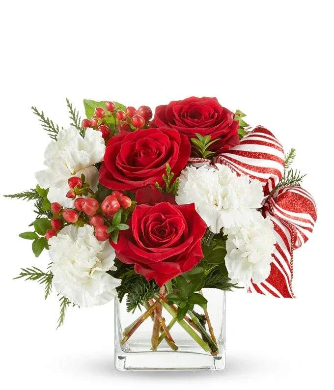 Candy Cane Kiss Candy Cane Kiss - A festive holiday arrangement featuring 3 large red roses, white hydrangea or carnations, sprigs of pine and winterberry, and a festive bow in short vase,