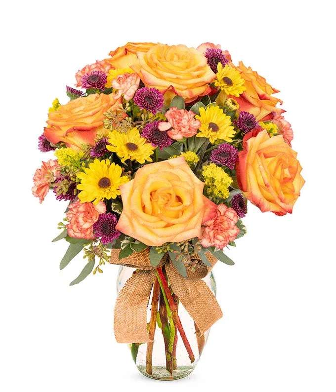 Rustic Charm Rustic Charm - A lush domed floral arrangement featuring peach and orange roses with fall themed flowers tied with a rustic burlap ribbon around a clear bubble vase.