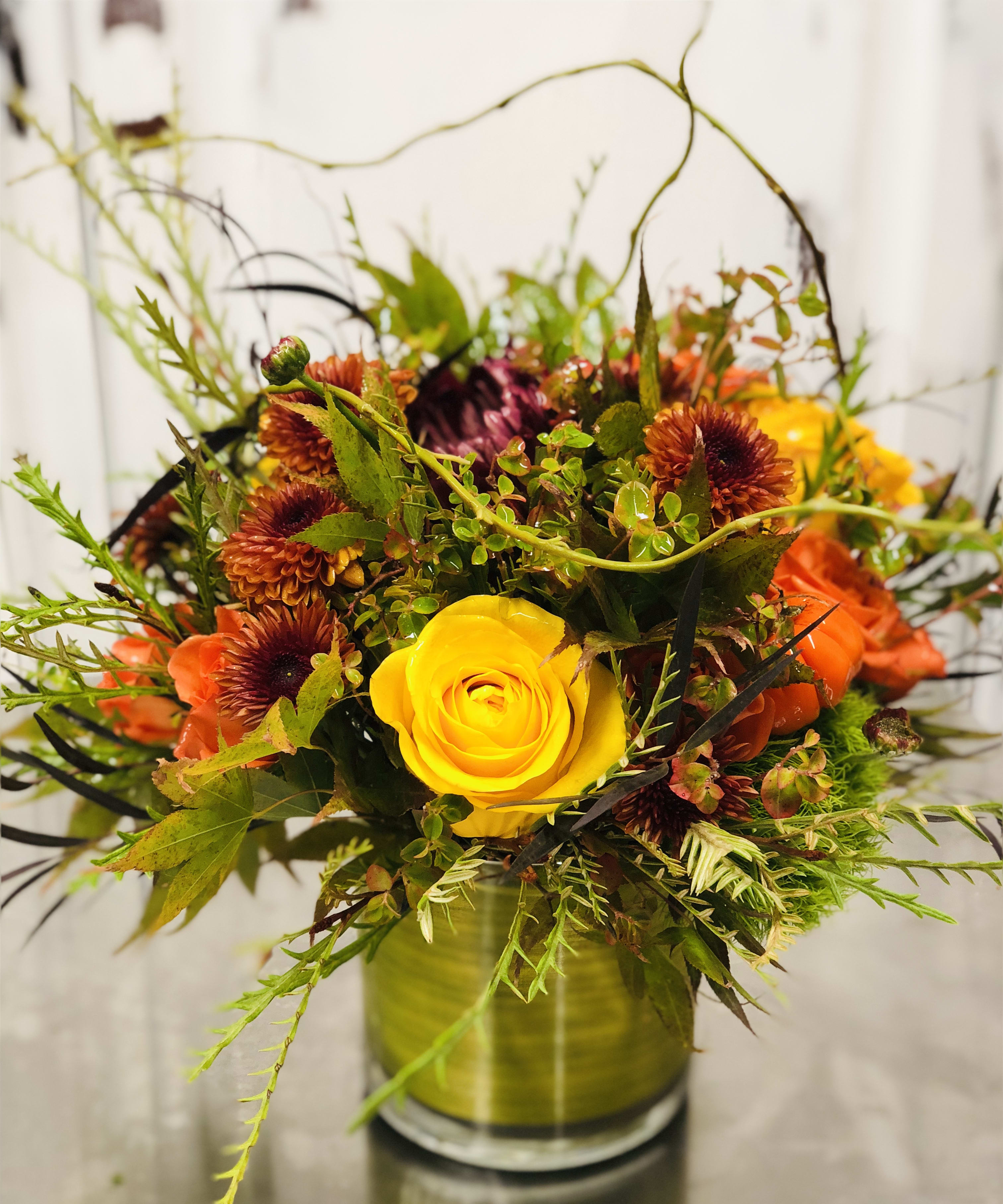 Fall Beauty Fall Beauty - This Fall beauty is a moody, bold, display of beautiful, in season, fall blooms at their finest. This Fall Design is guaranteed to get the autumn mood started. Brightly designed with Orange Spray Roses, Yellow garden Roses, Burnt orange Chrysanthemums, Green Trick Dianthus, Curly Willow, and fall greens in clear container. Florist reserves the right to make modifications based on availability due to COVID-19 disruptions in our supply chain. Kindly call us directly with any specifications or concerns.