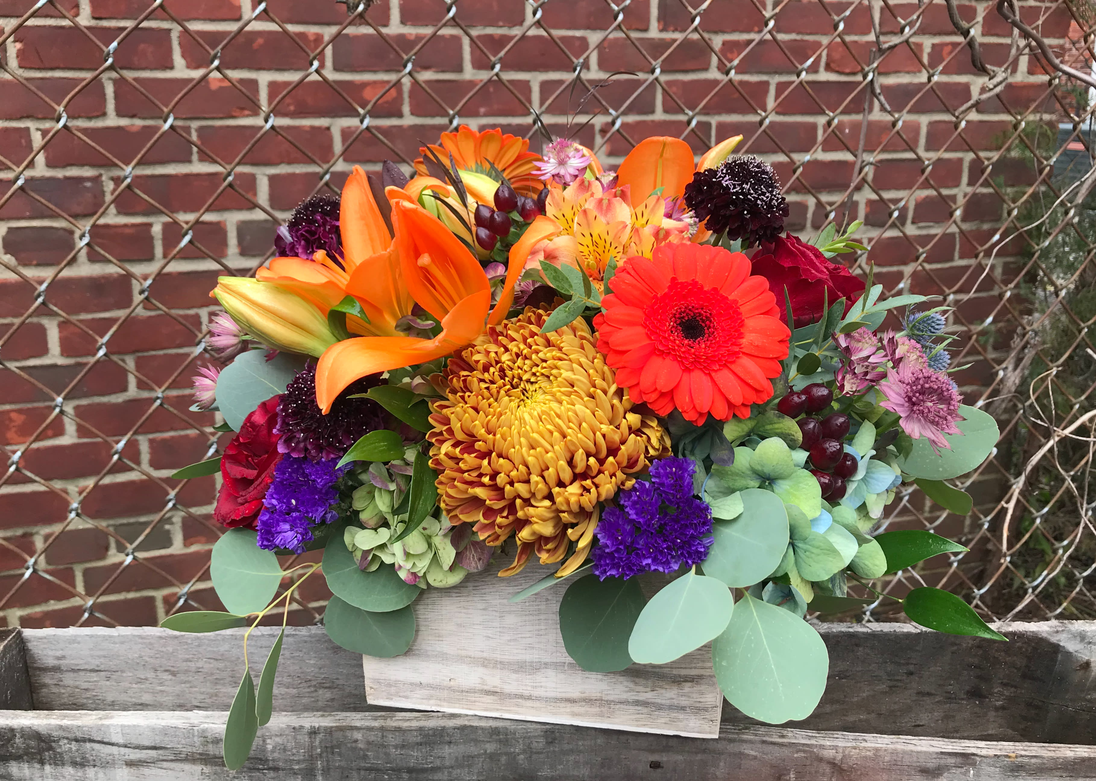 Autumn in New York - This wood crate overflows with an abundance of autumn's best!   Includes asiatic lilies, mums, gerbera daisies, roses, peruvian lilies, eucalyptus, hydrangea, hypericum berries all in splendid fall tones.  